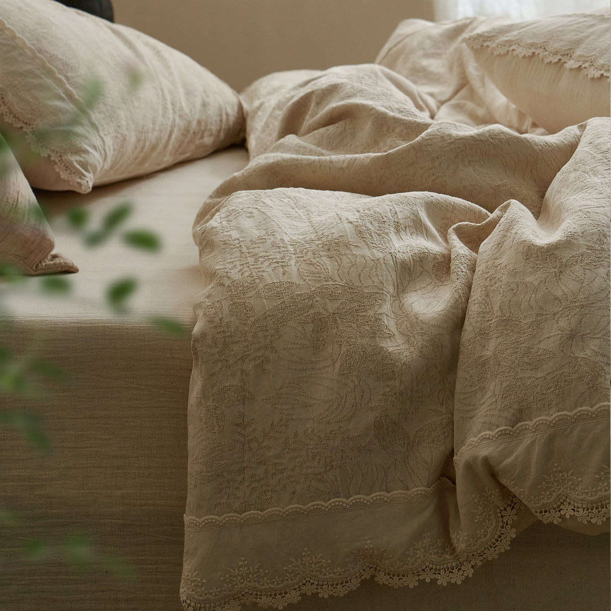 Side view of a warm beige cotton-linen duvet cover set with relaxed draping and coordinating pillow shams.
