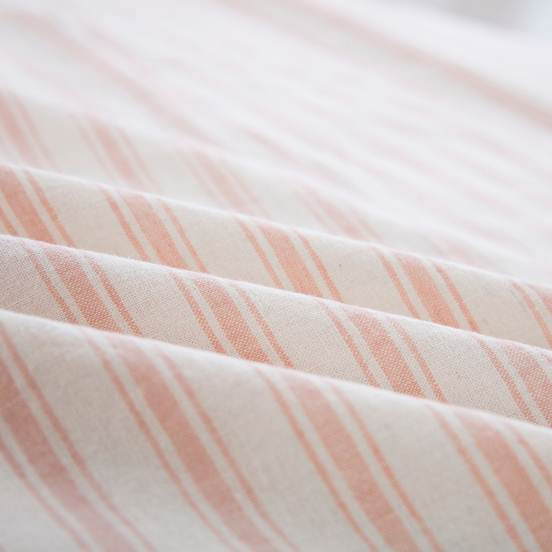 Close-up of the tactile lived-in texture and richer color depth of the yarn-dyed blush pink striped sheet fabric - DAUAOTO
