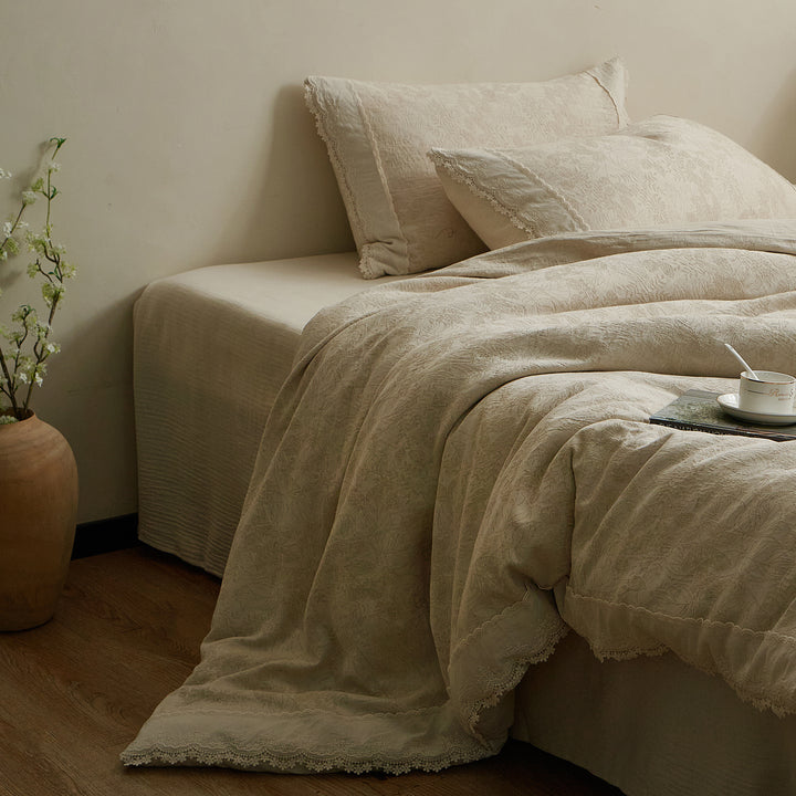 Side view of a warm beige cotton-linen duvet cover set with relaxed draping and coordinating pillow shams.