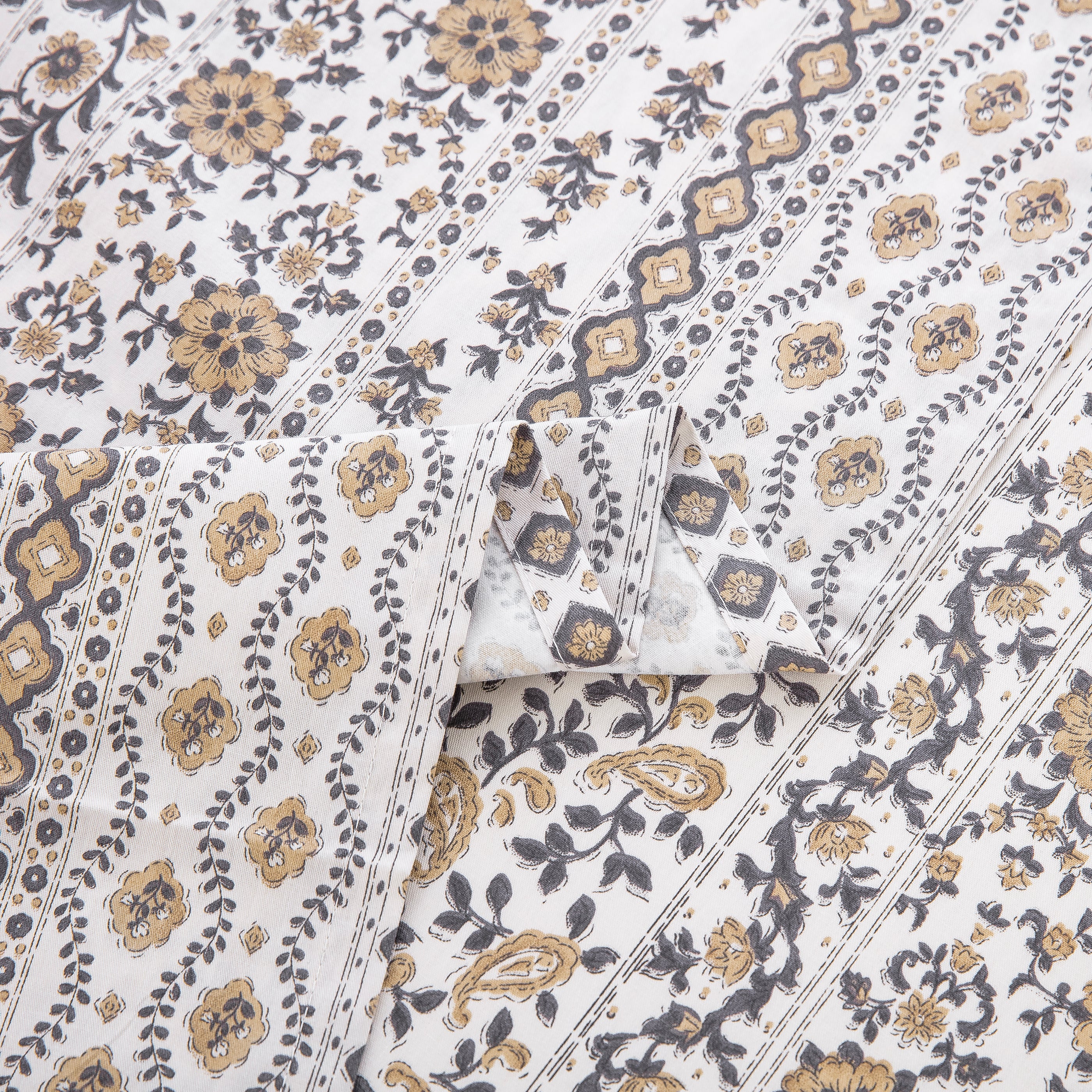 Close-up showing the elegant folded edges and earthy geometric print of the DAUAOTO bohemian cotton sheets.