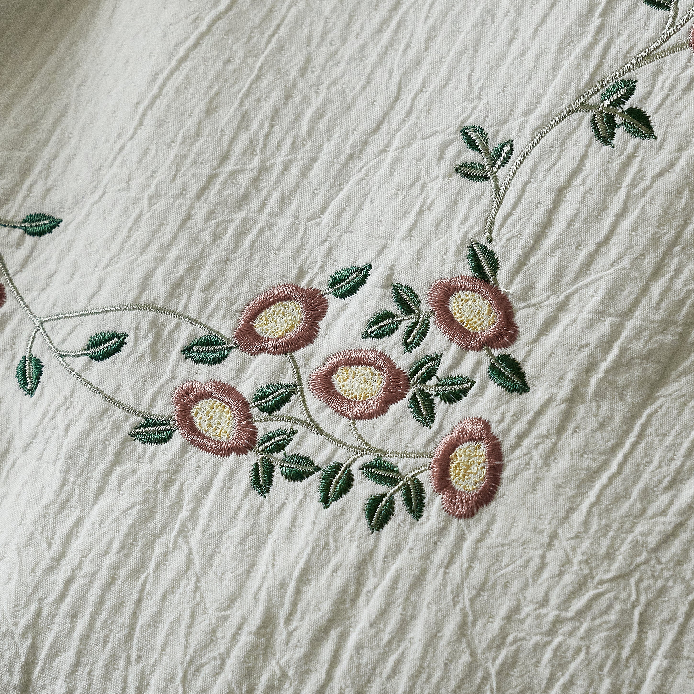 Close-up of dusty rose floral embroidery on textured washed cotton