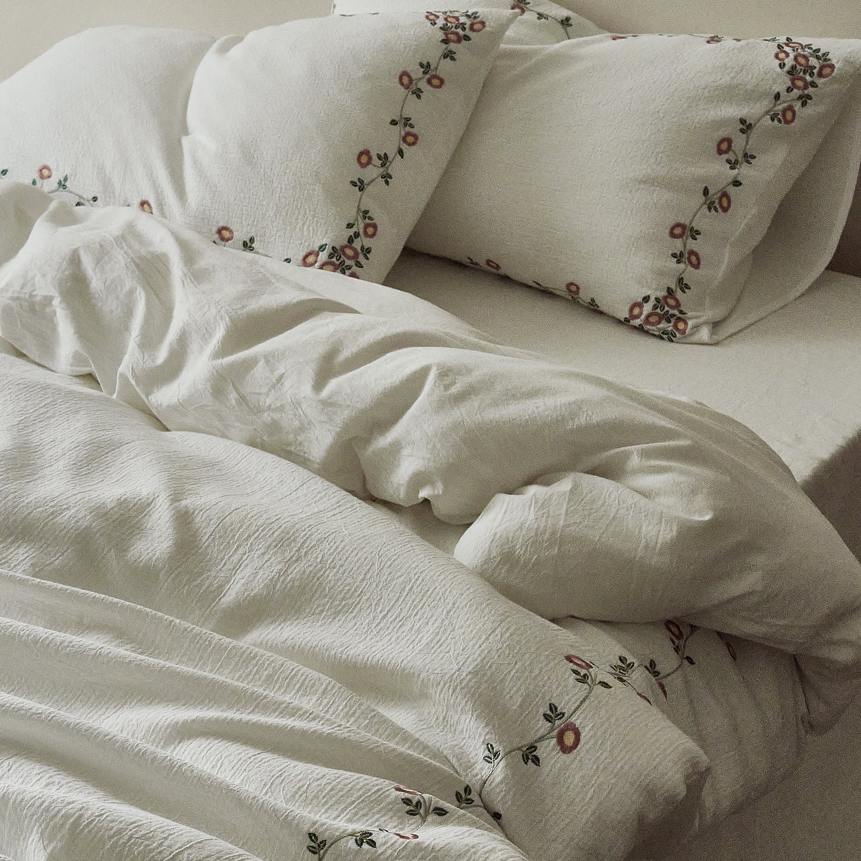 Side view of the Briar Bloom embroidered bedding with soft natural folds