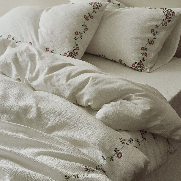 Side view of the Briar Bloom embroidered bedding with soft natural folds