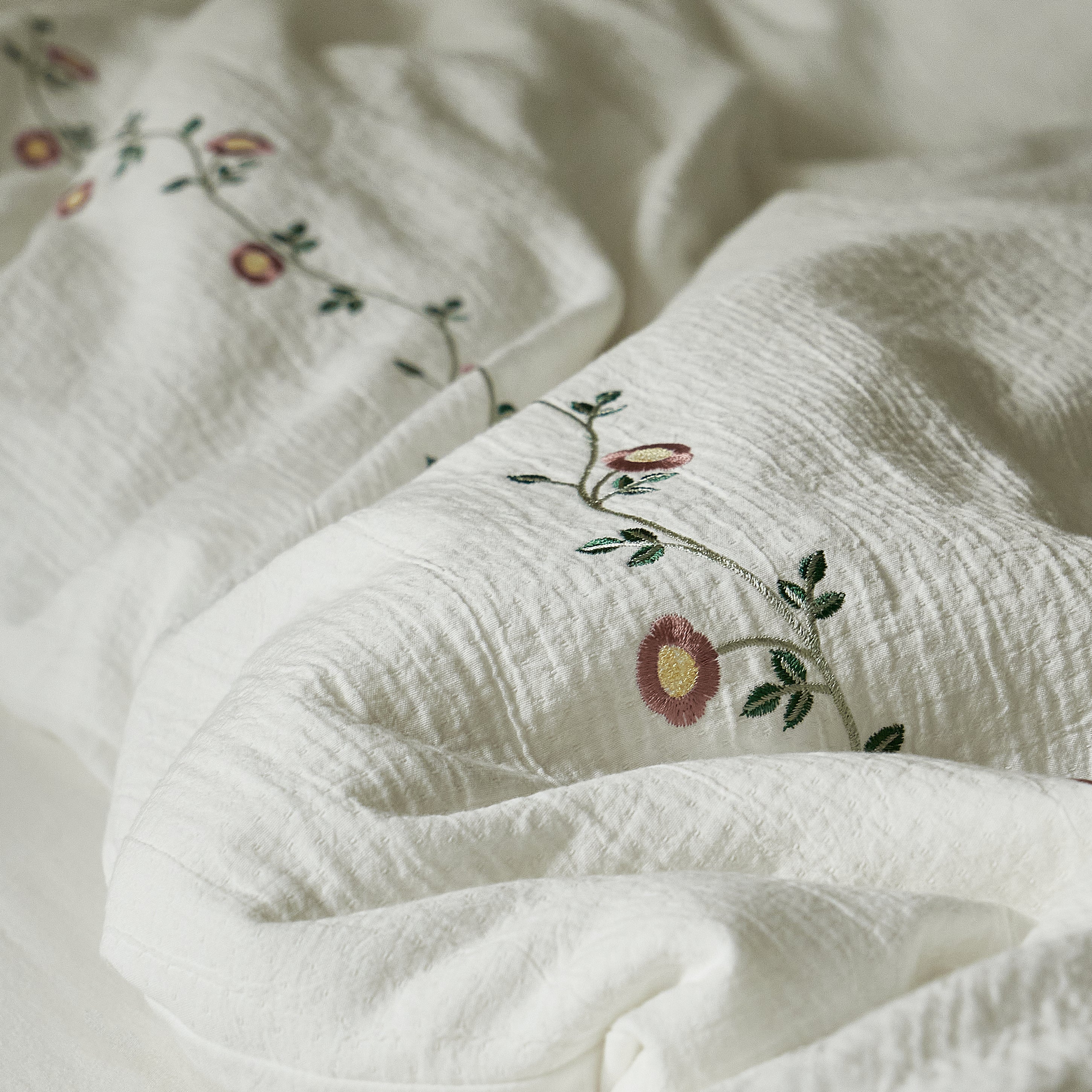 Close-up of the naturally crinkled washed cotton texture and floral embroidery