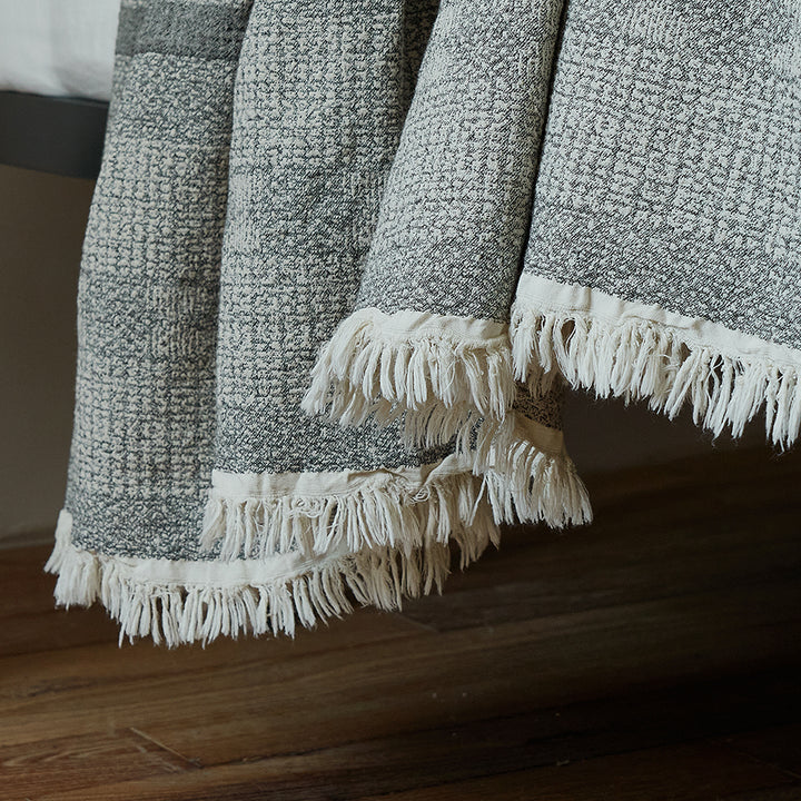 Close-up of the delicate fringe edge on the charcoal black jacquard woven striped throw.