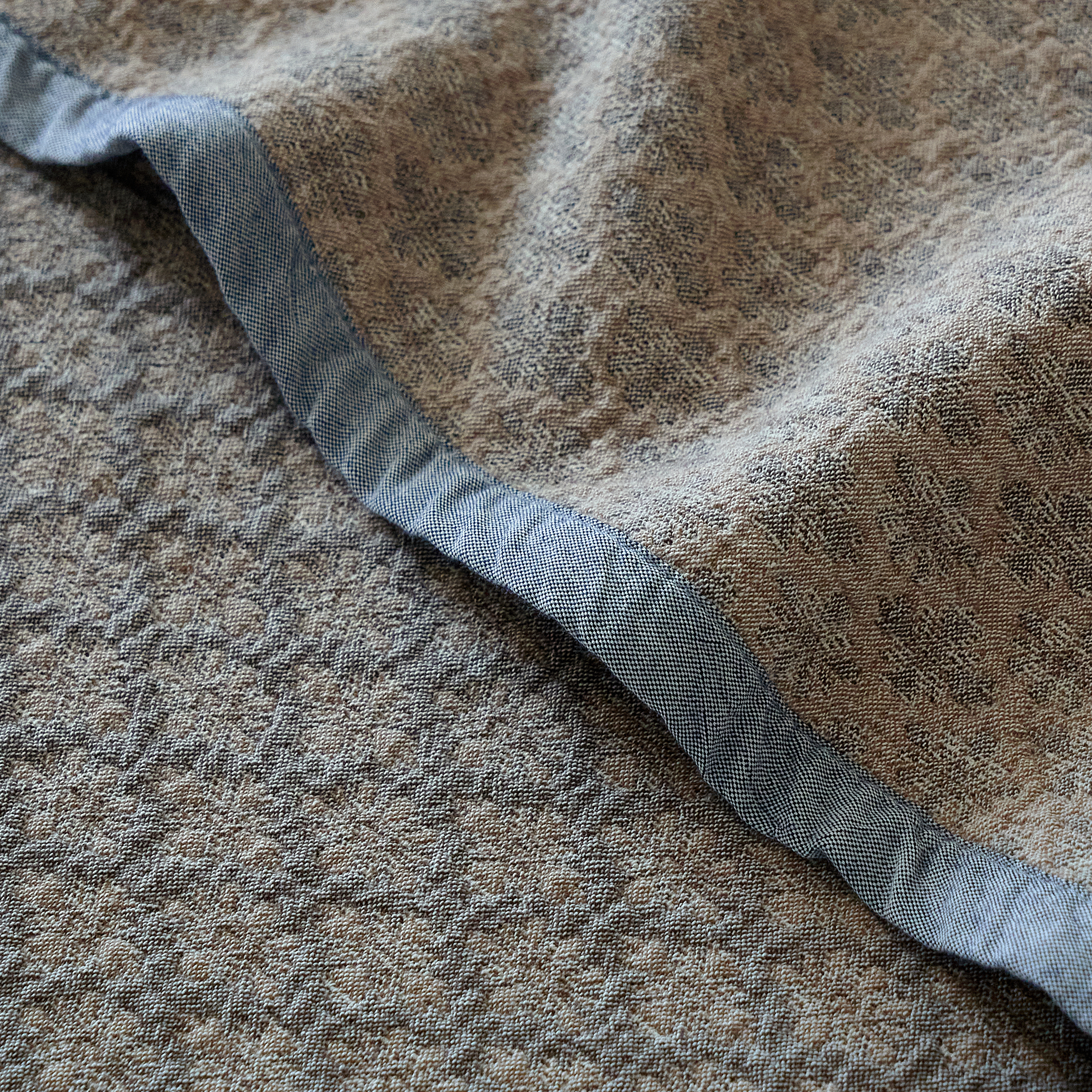 Detail shot of the tailored narrow bound edge on the heavyweight charcoal gray cotton coverlet.