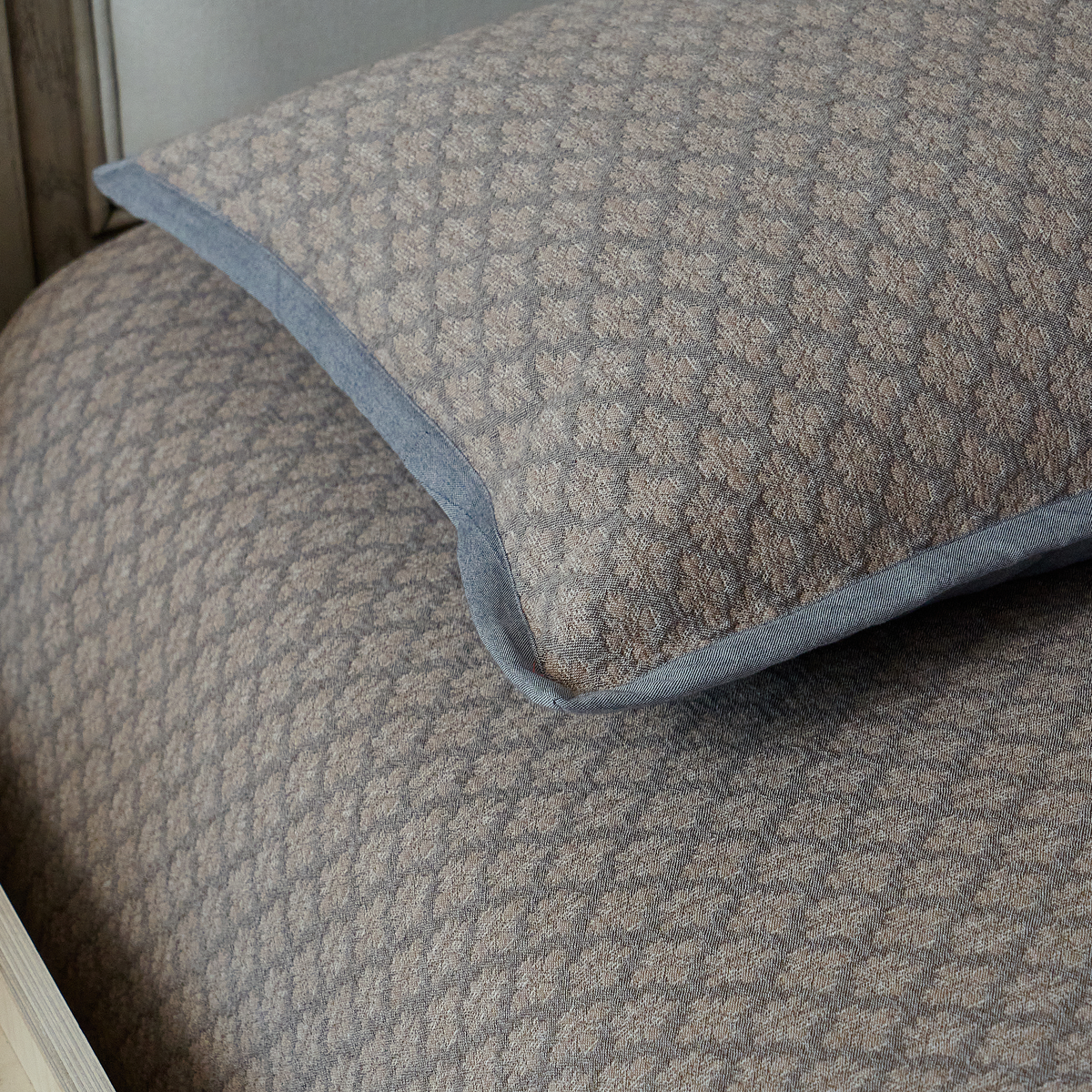 Close-up of the structured corner detailing on the charcoal gray diamond jacquard pillow sham.