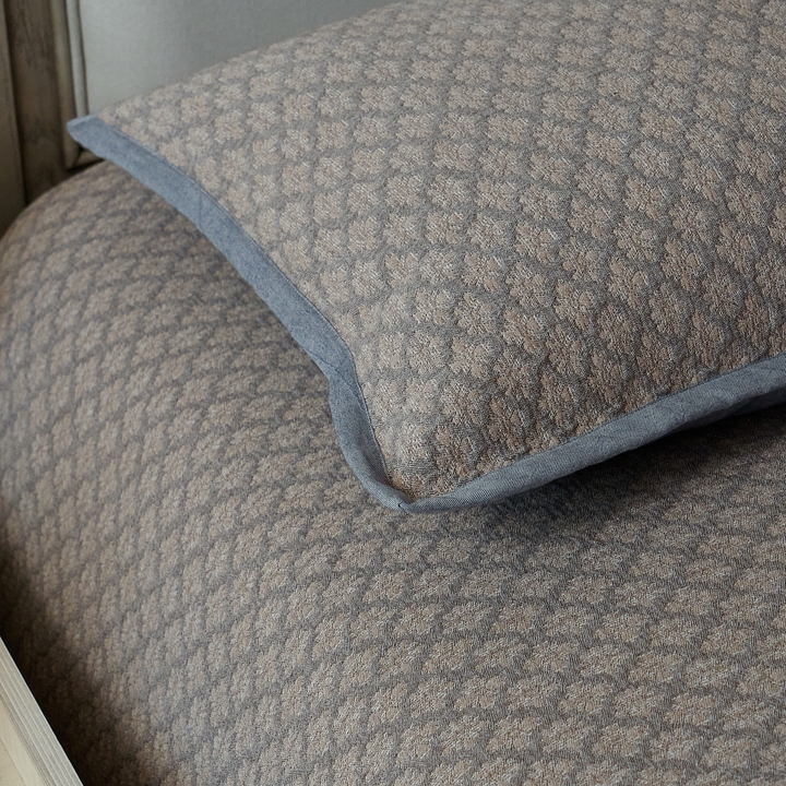 Close-up of the structured corner detailing on the charcoal gray diamond jacquard pillow sham.