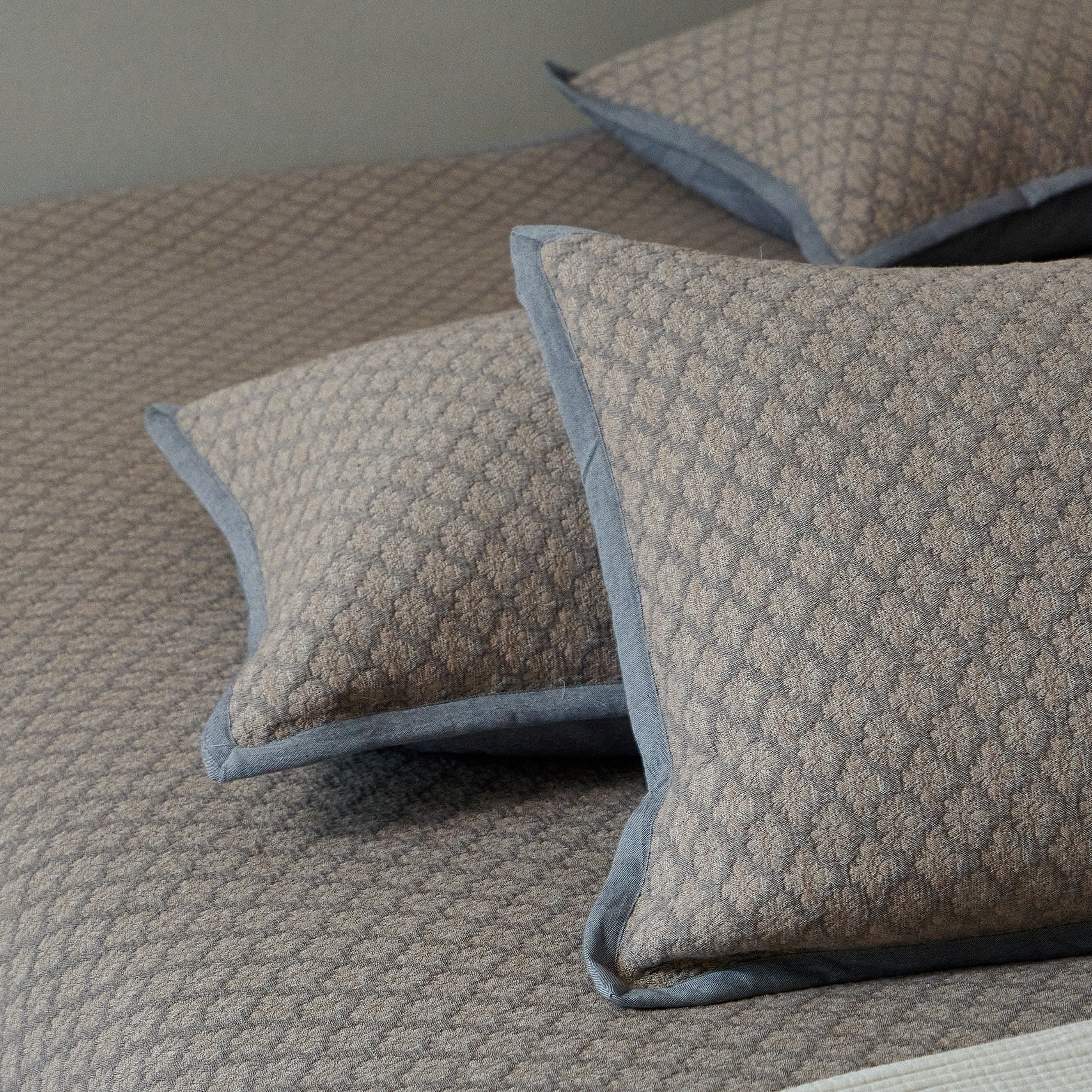 Layered charcoal gray textured pillow shams on a sleek modern bed.