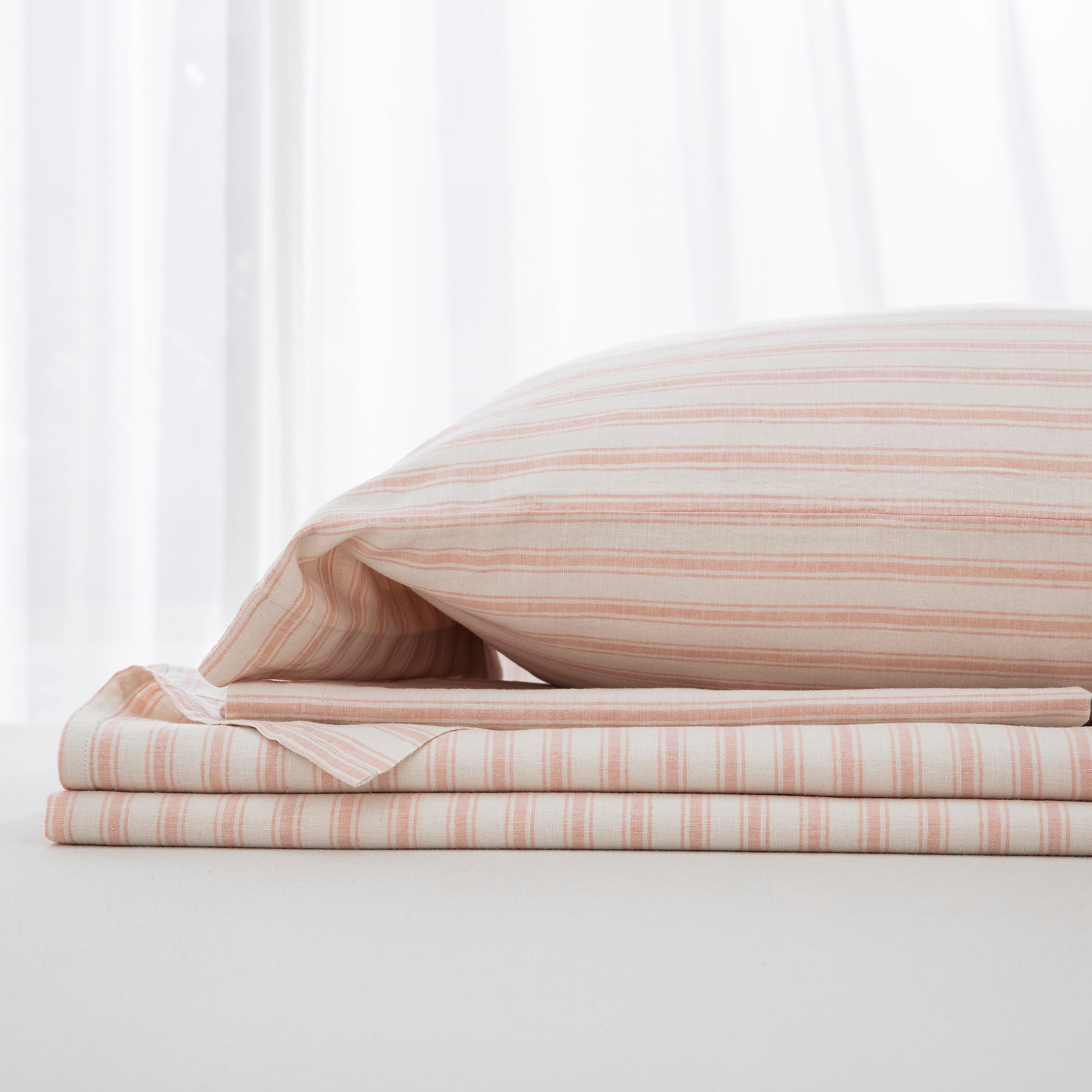 Complete blush pink yarn-dyed stripe linen cotton bedding ensemble folded neatly showcasing romantic warmth - DAUAOTO