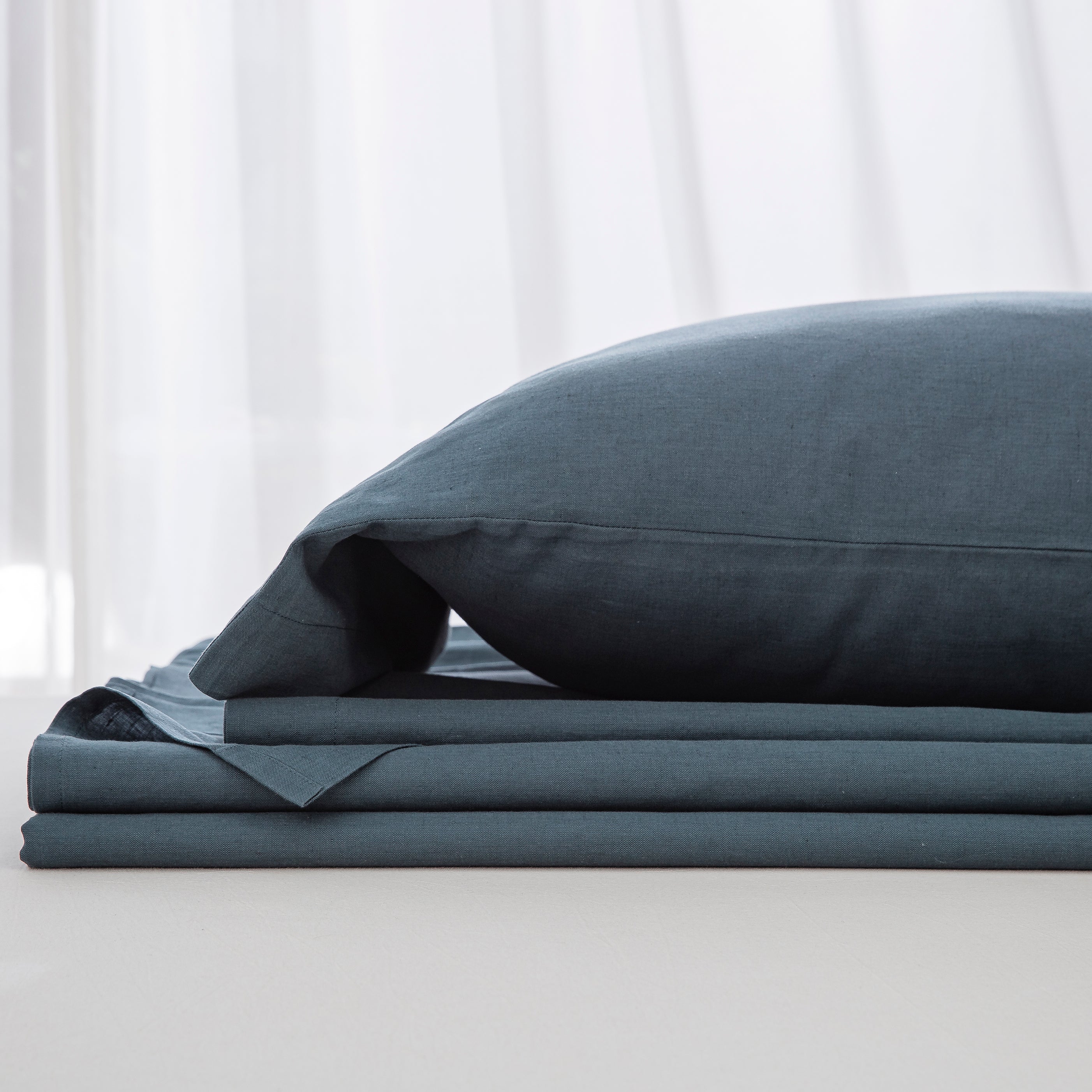 Complete midnight slate blue linen cotton bedding ensemble folded neatly showcasing a relaxed yet refined foundation - DAUAOTO