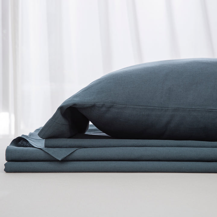 Complete midnight slate blue linen cotton bedding ensemble folded neatly showcasing a relaxed yet refined foundation - DAUAOTO