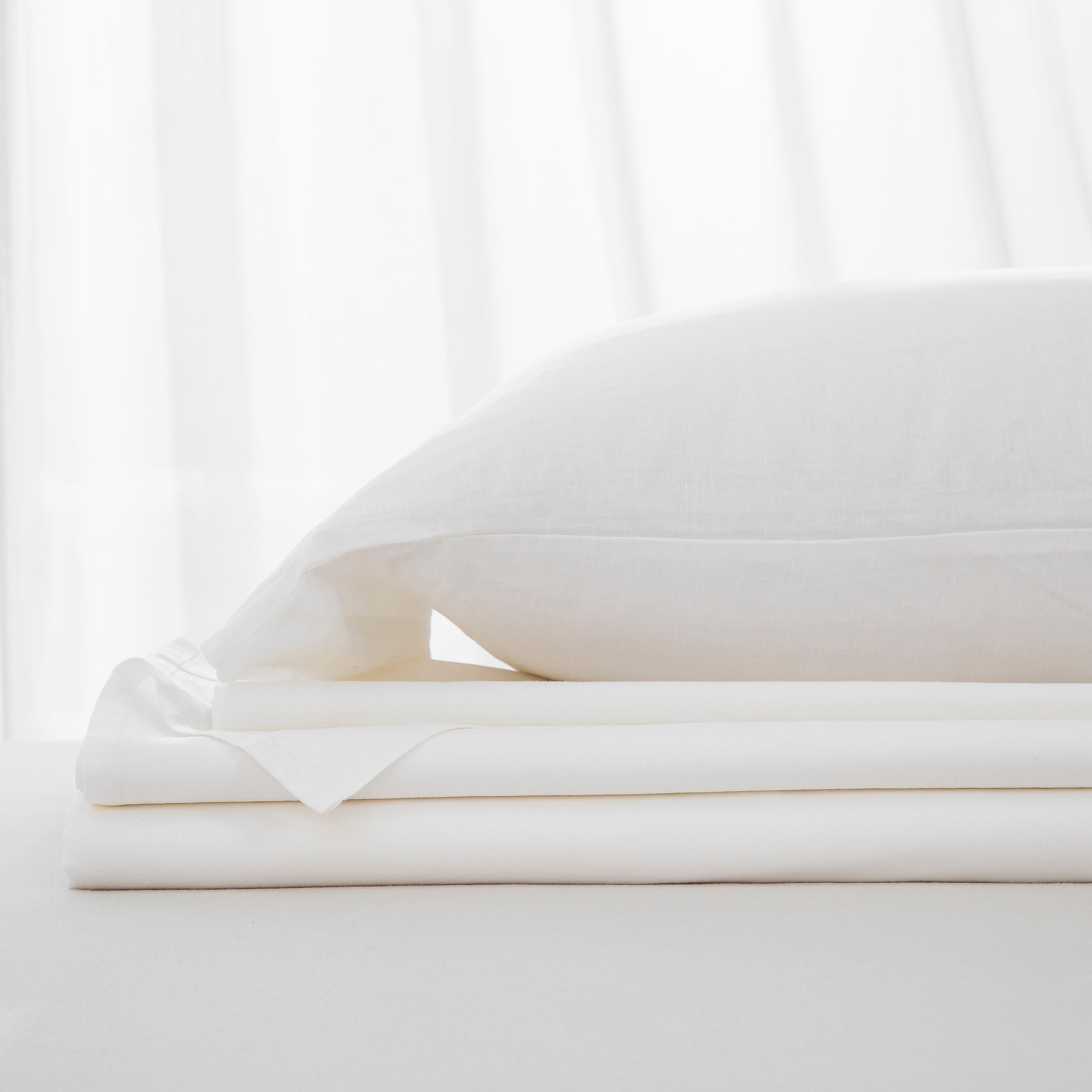 Complete white linen cotton bedding ensemble folded neatly for a bright and restorative night's sleep - DAUAOTO