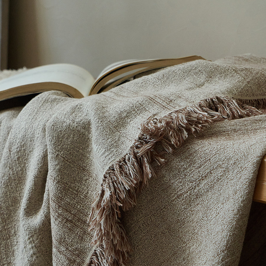 Warm sand textured throw blanket with a book, perfect for a cozy reading nook setting.