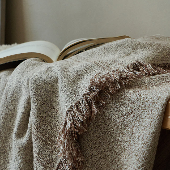 Warm sand textured throw blanket with a book, perfect for a cozy reading nook setting.