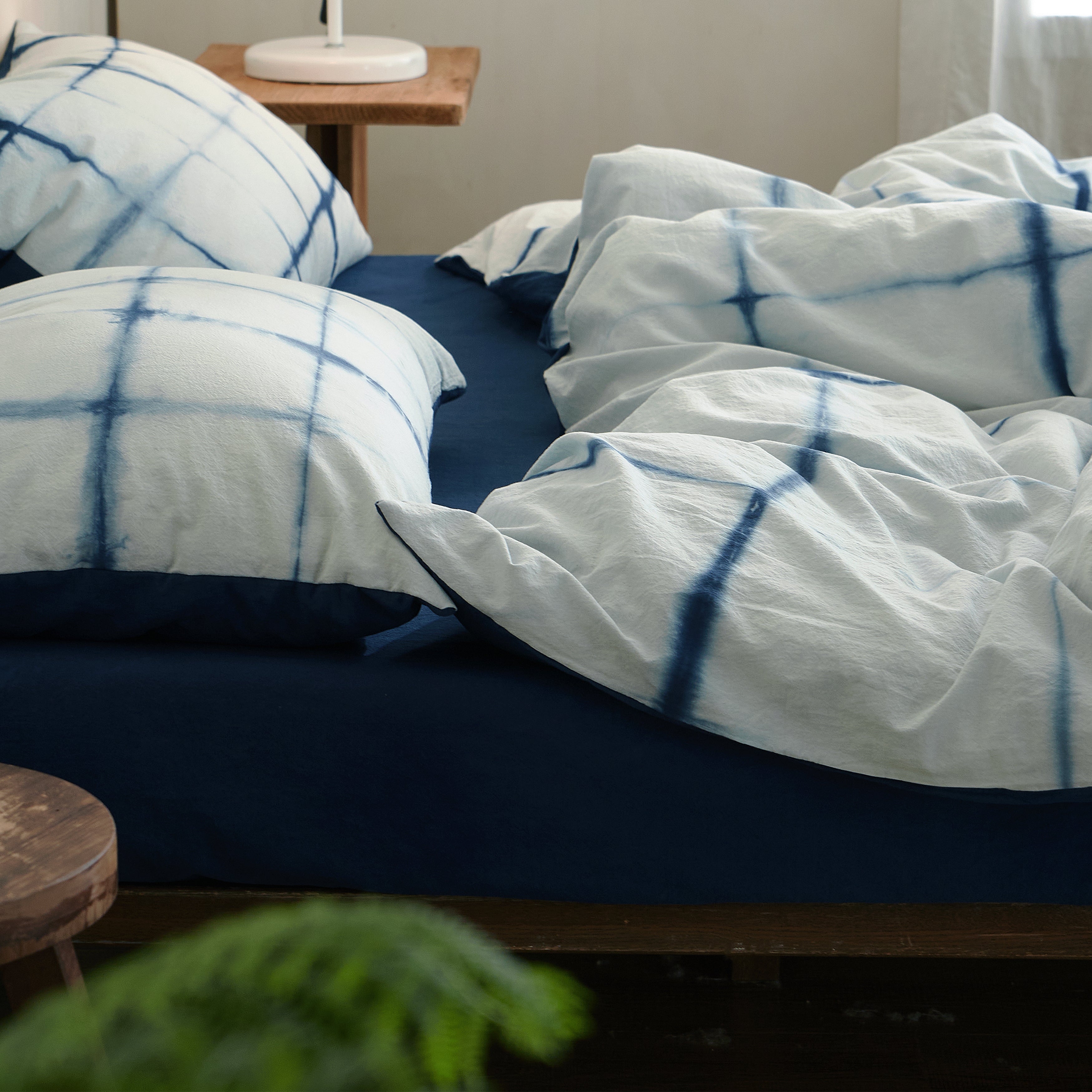 Soft, breathable drape of the DAUAOTO Artisan Grid 100% cotton tie-dye duvet cover on a messy bed