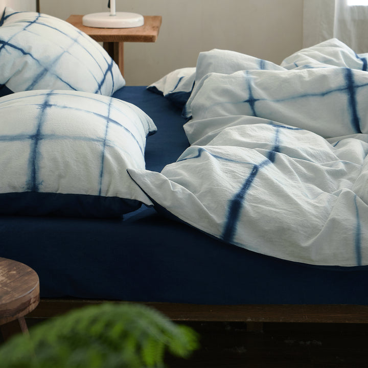 Soft, breathable drape of the DAUAOTO Artisan Grid 100% cotton tie-dye duvet cover on a messy bed