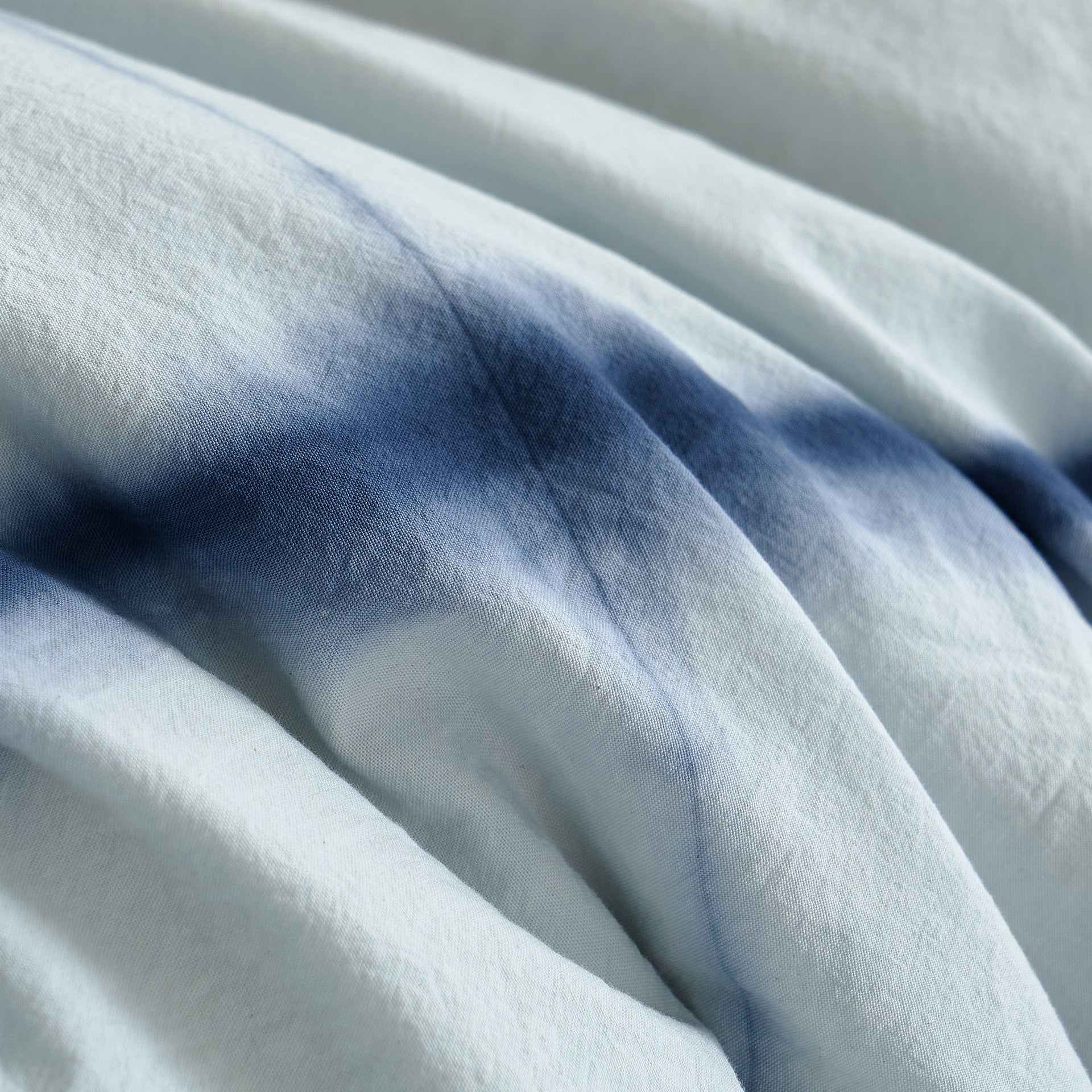 Macro detail of the hand-dyed botanical indigo intersecting lines on DAUAOTO's 100% pure white cotton fabric