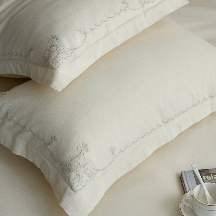 Close-up of stacked Aveline pillow shams featuring scalloped embroidered borders.