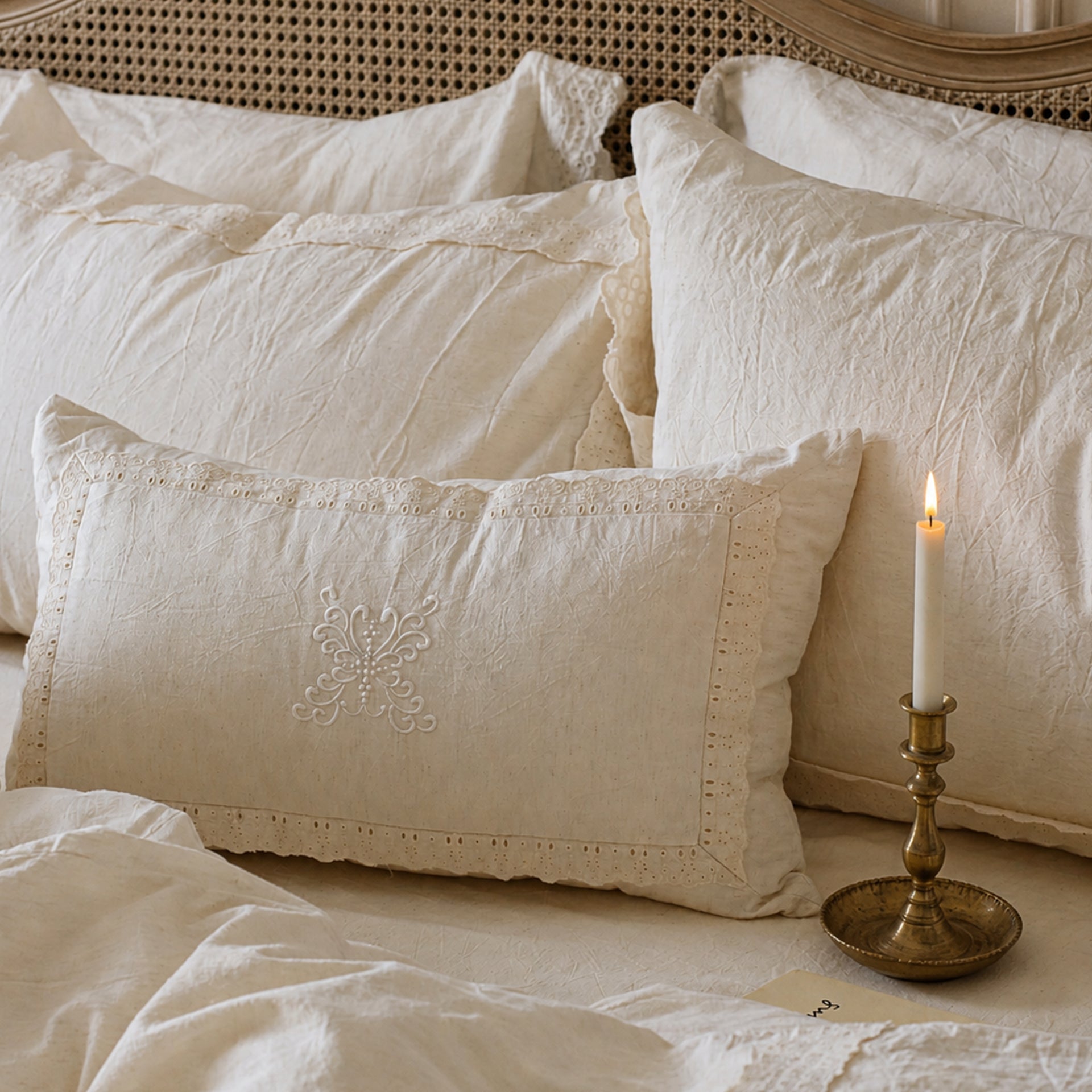 Close-up of the Fontainebleau cotton linen pillowcases featuring heavy custom lace and a candle in the background.