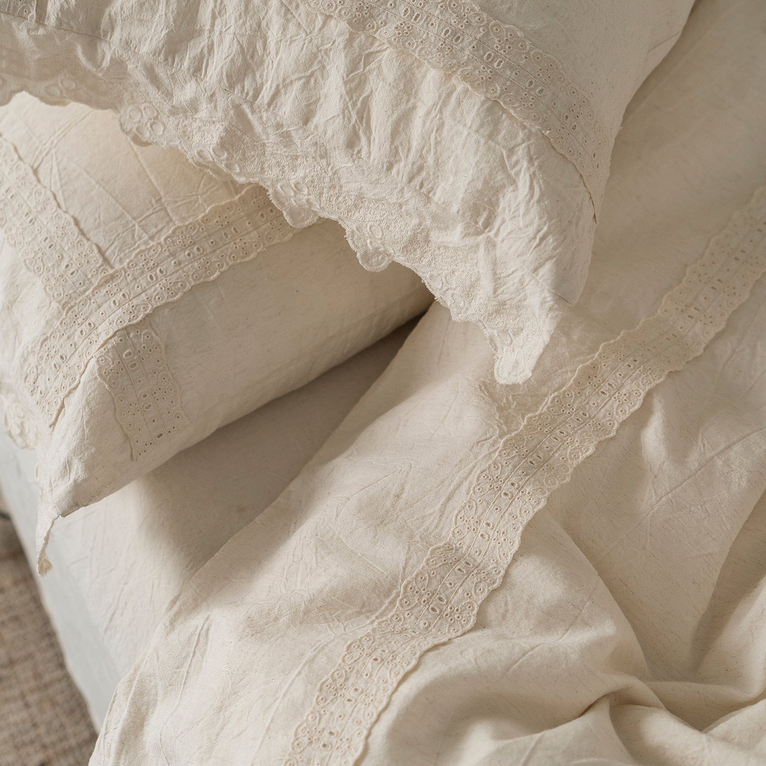 Close-up of the Fontainebleau cotton-linen duvet cover and pillow shams in natural ivory, featuring vintage embroidery and scalloped lace trim.