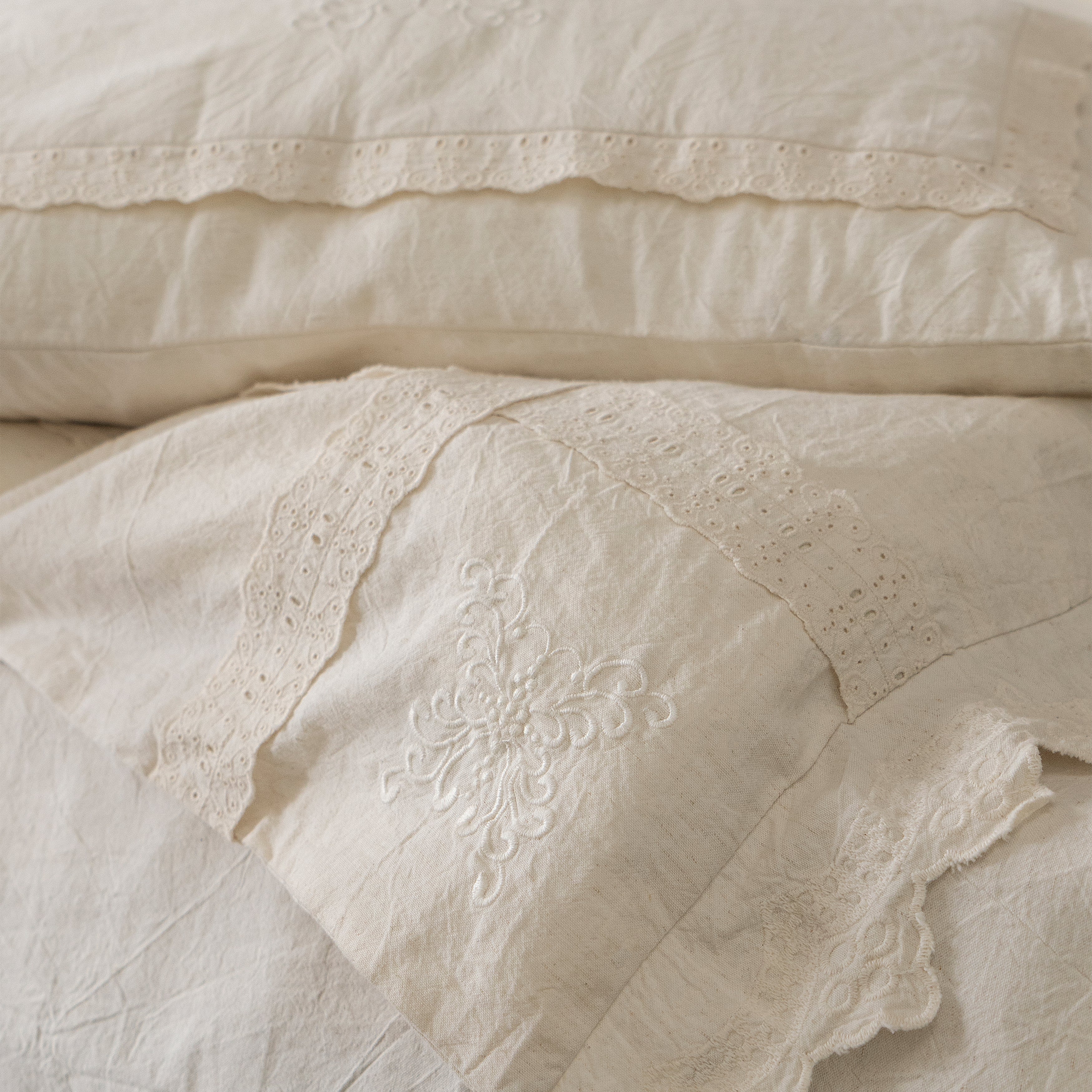 Close-up of the folded Fontainebleau bedding, displaying the layered lace edges and soft natural fabric.