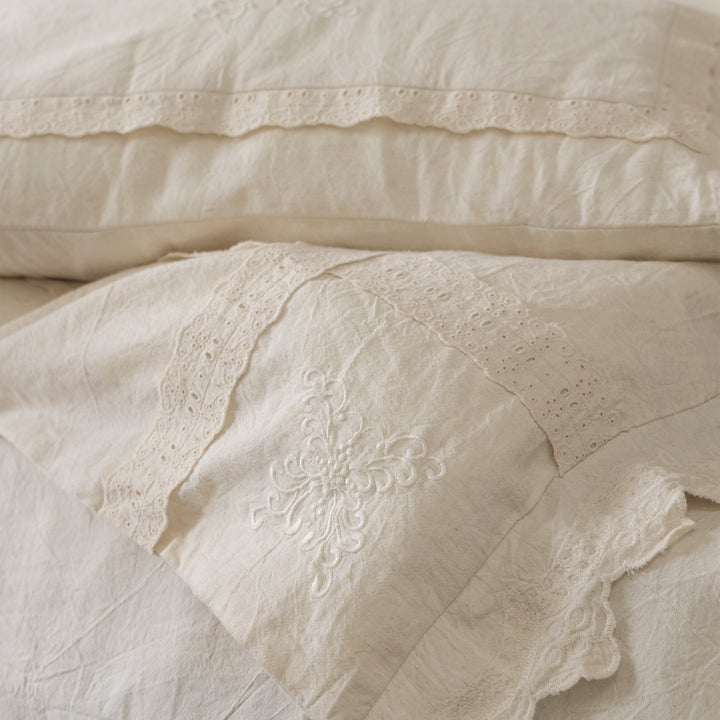 Close-up of the folded Fontainebleau bedding, displaying the layered lace edges and soft natural fabric.