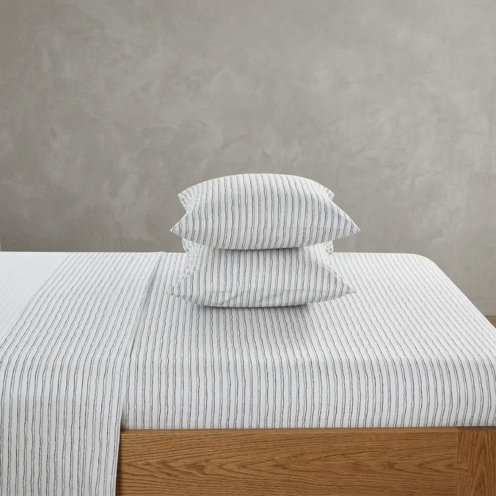 Modern minimalist bedroom featuring the DAUAOTO hand-painted stripe 100% cotton sheet set in soft blue and charcoal tones