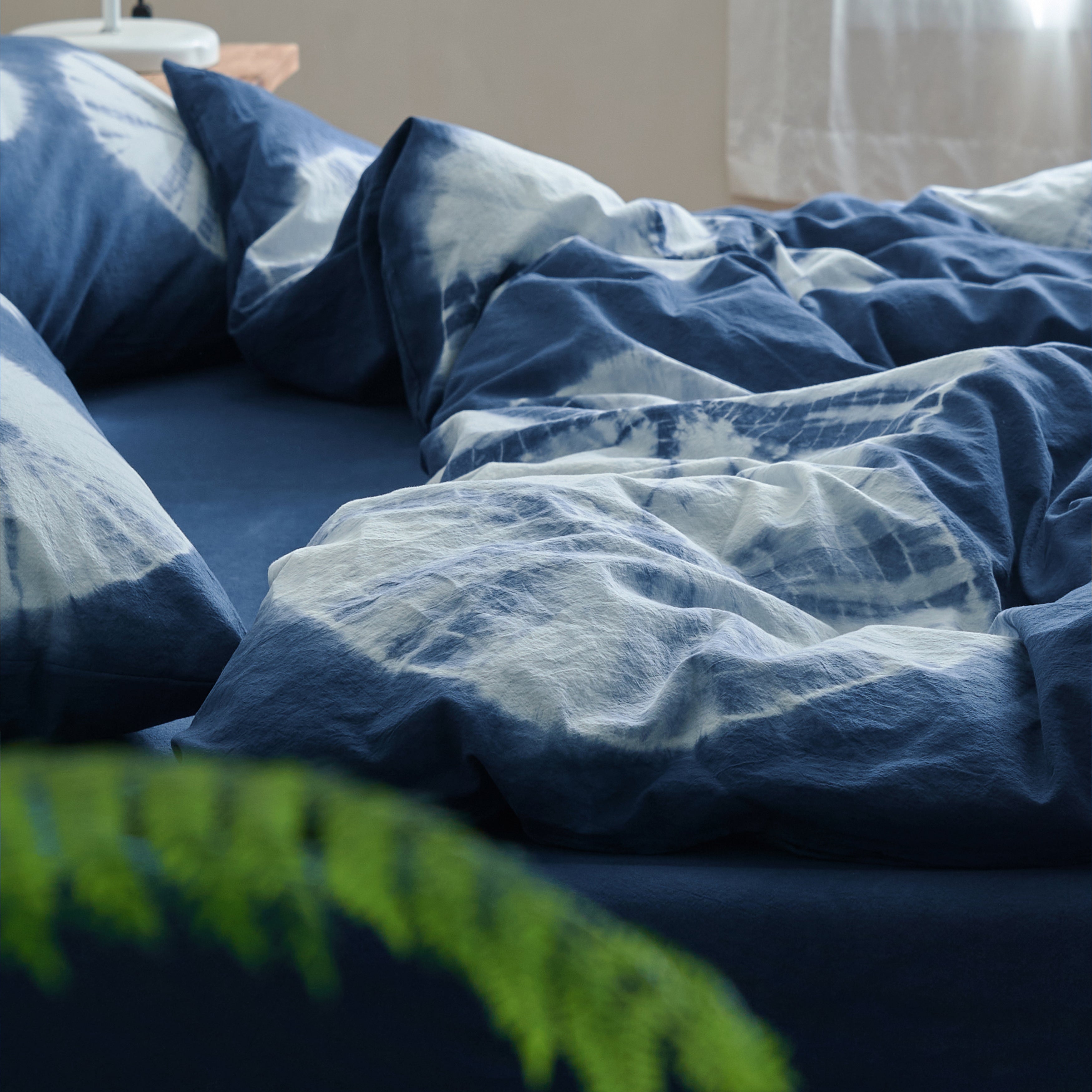 Relaxed, draped look of the DAUAOTO Indigo Bloom handmade duvet cover set, highlighting the organic dye edges.