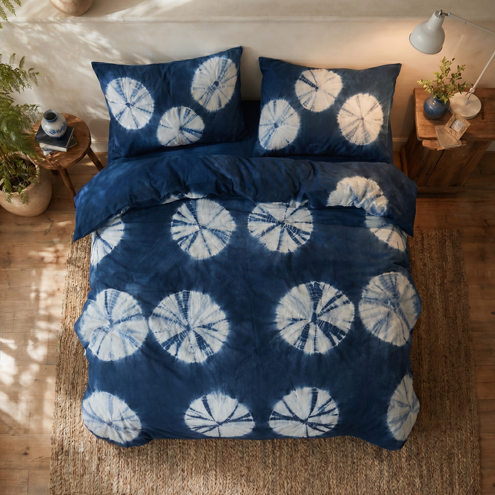 Top-down view of the DAUAOTO Indigo Bloom duvet cover and matching pillowcases showing the striking white sunburst pattern.