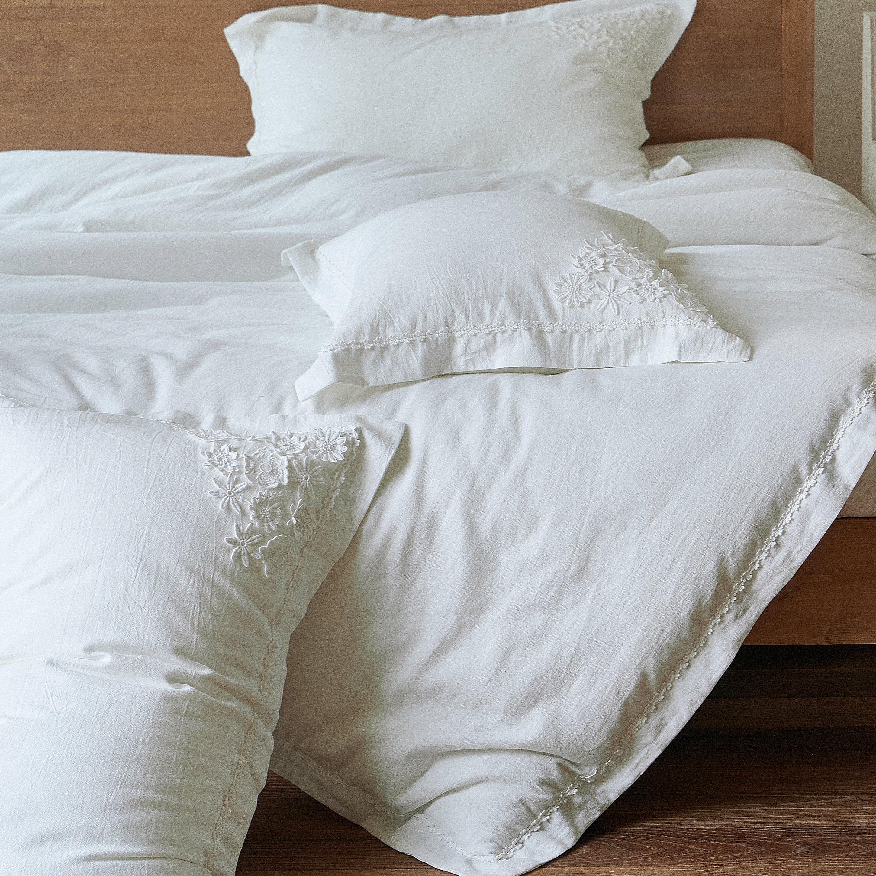 Morning Meadow white duvet cover and embroidered pillow shams displayed together on the bed.