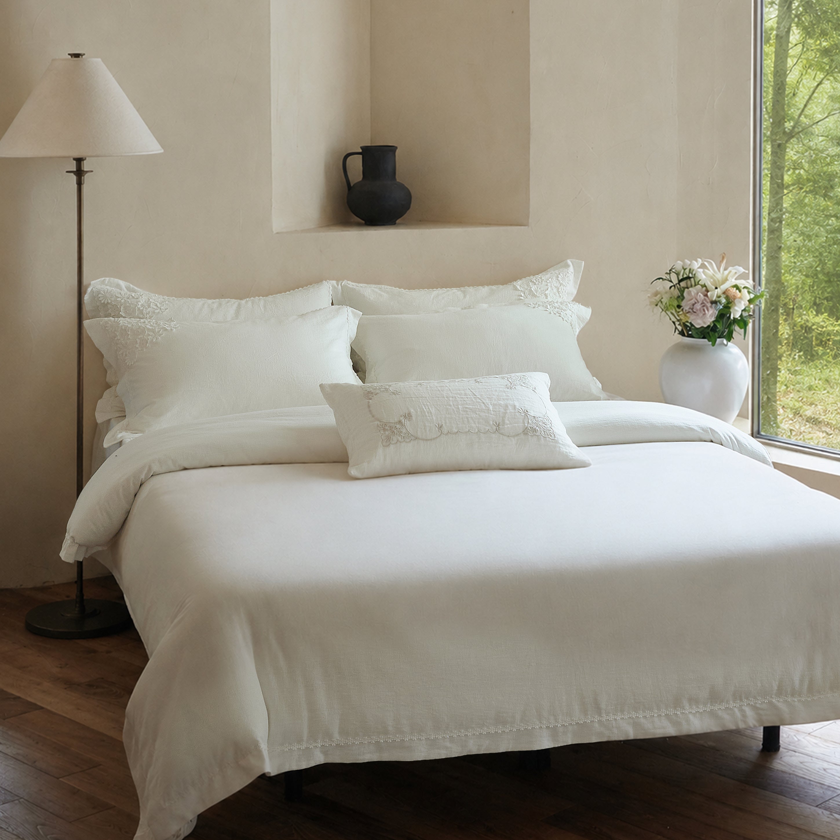 Front view of the Morning Meadow white embroidered cotton duvet cover set in a warm neutral bedroom.