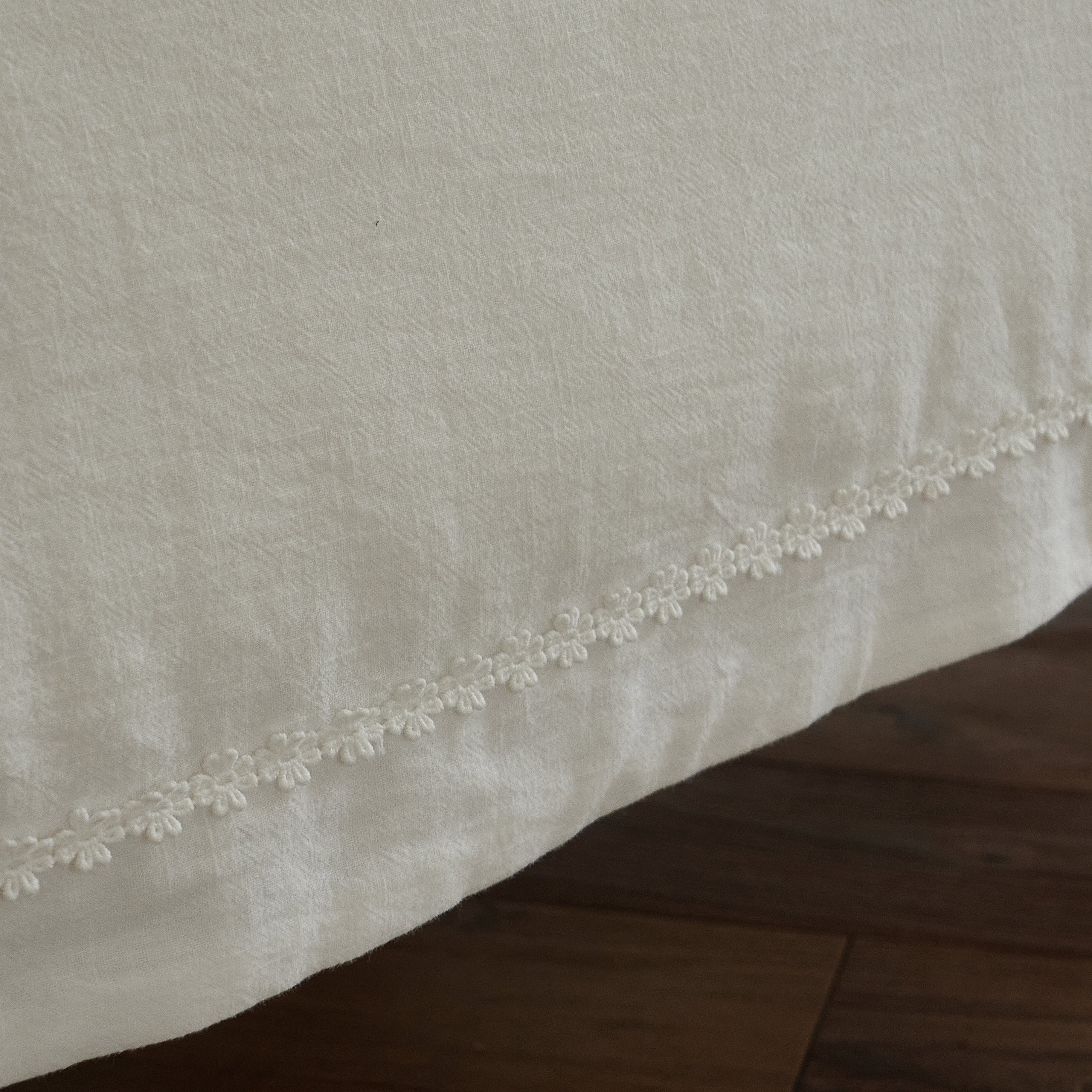 Textured white cotton duvet cover edge finished with delicate tone-on-tone floral trim.