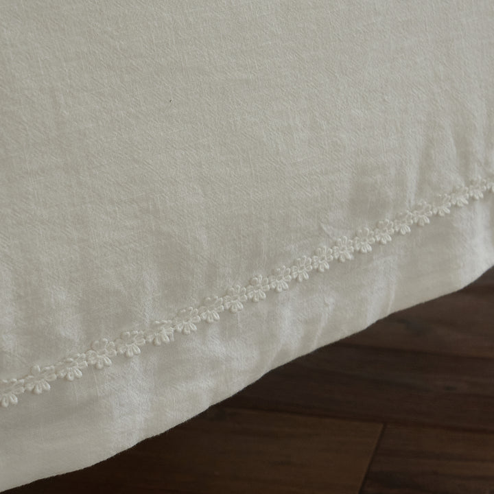 Textured white cotton duvet cover edge finished with delicate tone-on-tone floral trim.