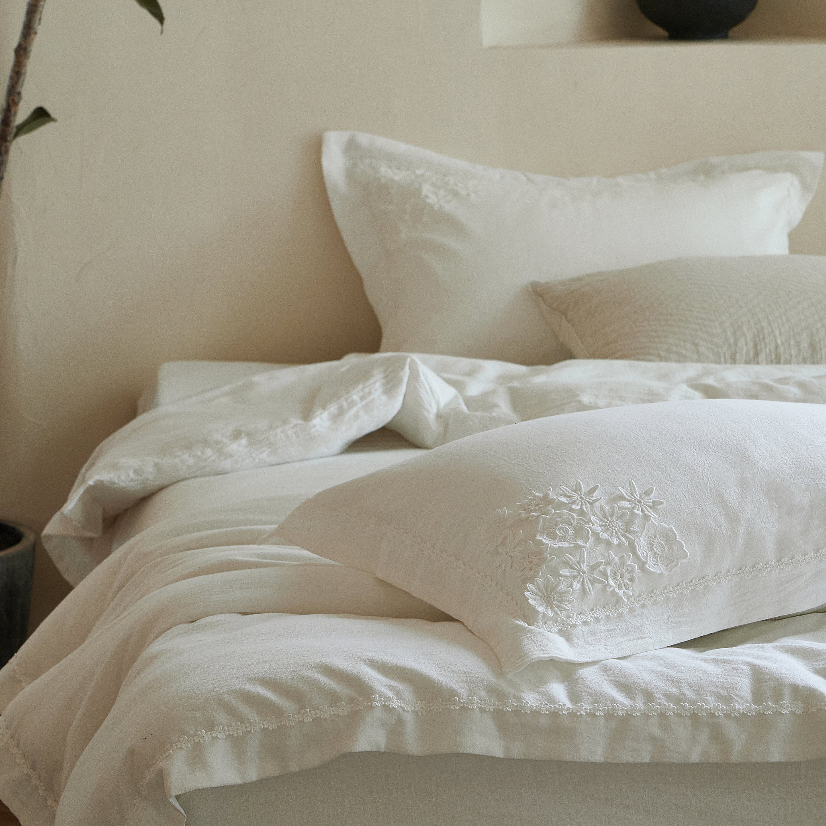 Morning Meadow white cotton duvet cover set styled in a warm neutral bedroom with botanical embroidery and delicate floral trim.