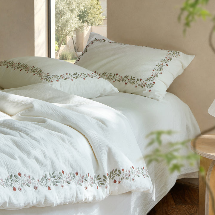 Rosebud Garland white washed cotton duvet cover and embroidered pillow shams styled beside a sunlit window.