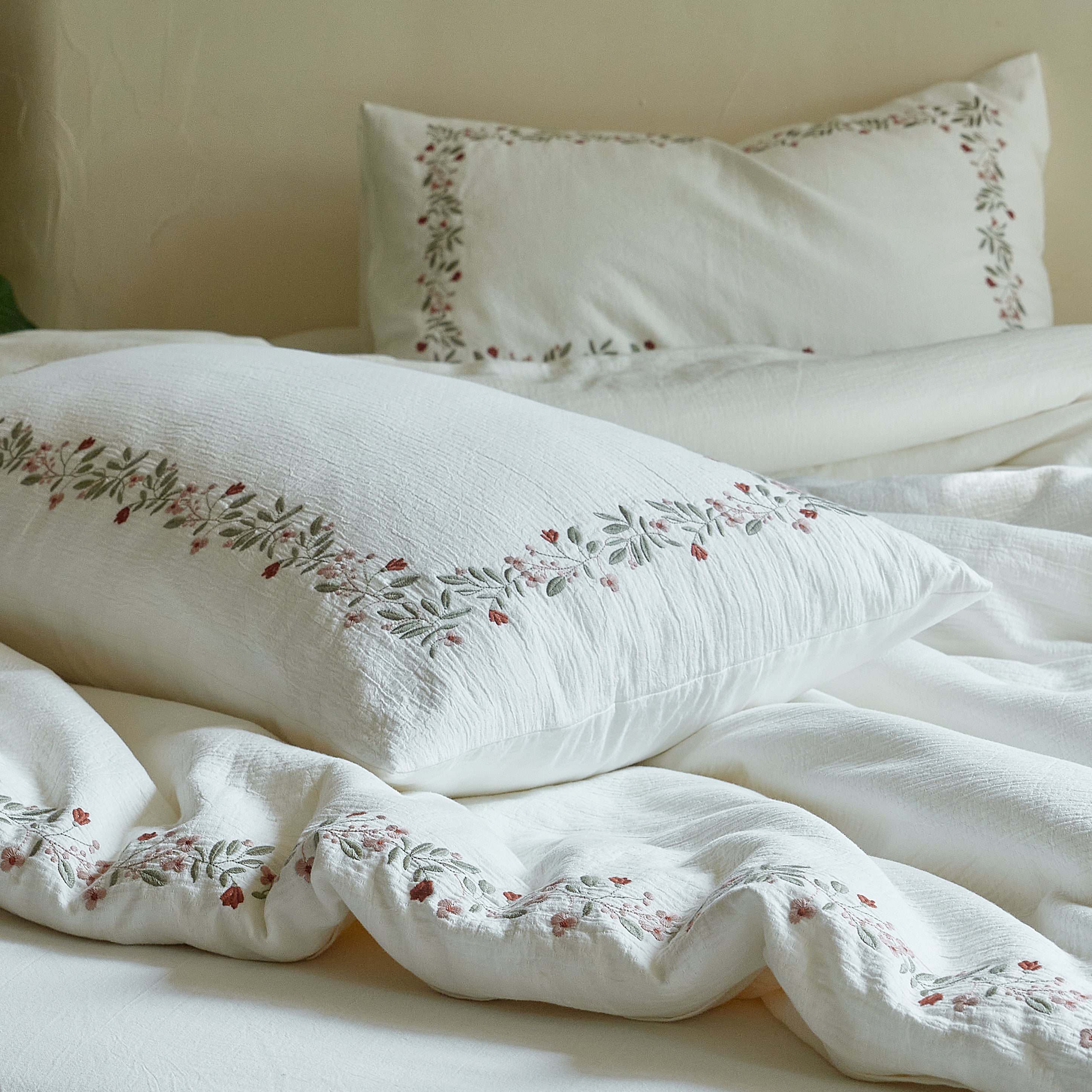 Close-up of the naturally puckered washed cotton and raised botanical embroidery on the Rosebud Garland bedding.