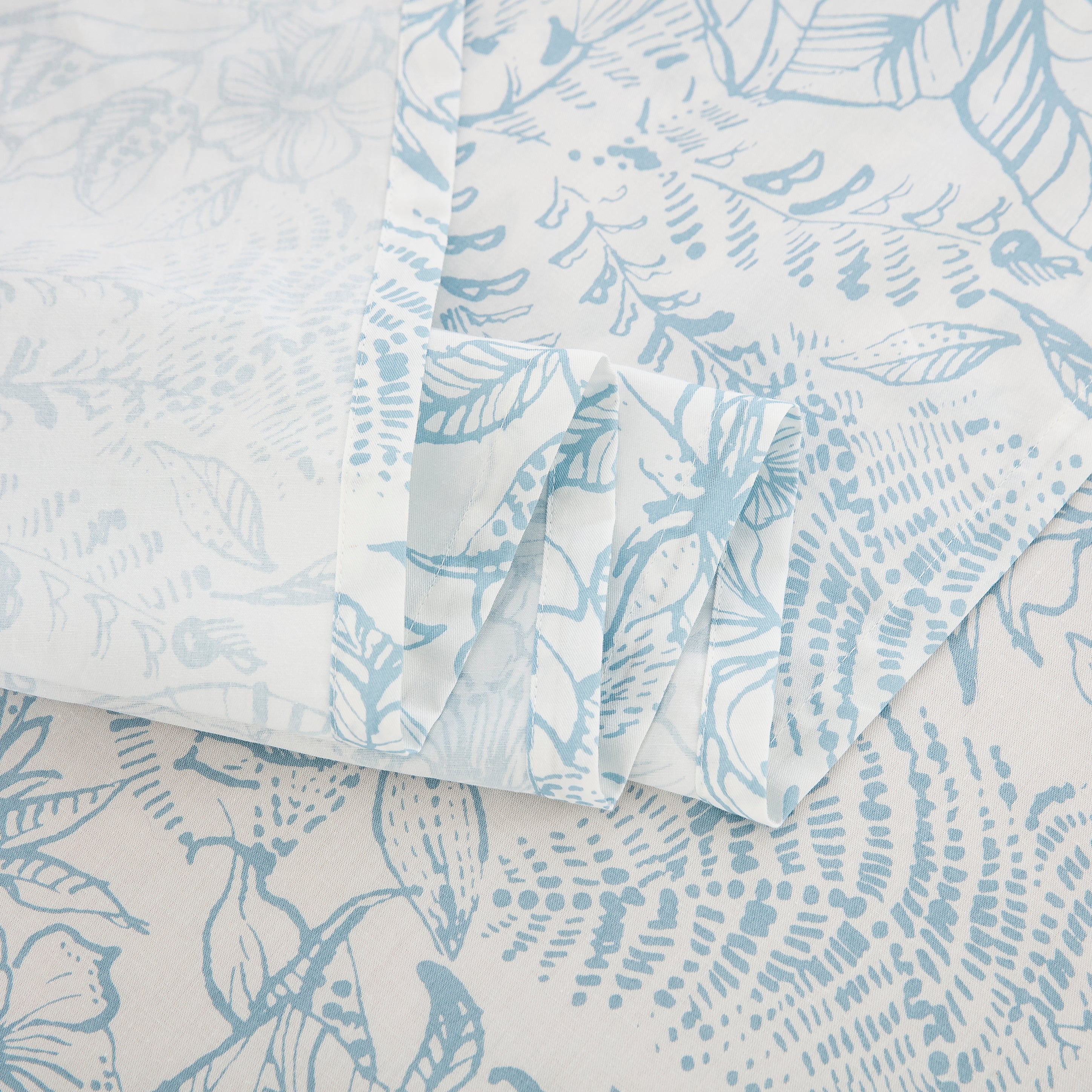 Detailed view of the delicately drawn light blue floral vine gracefully winding across off-white cotton - DAUAOTO