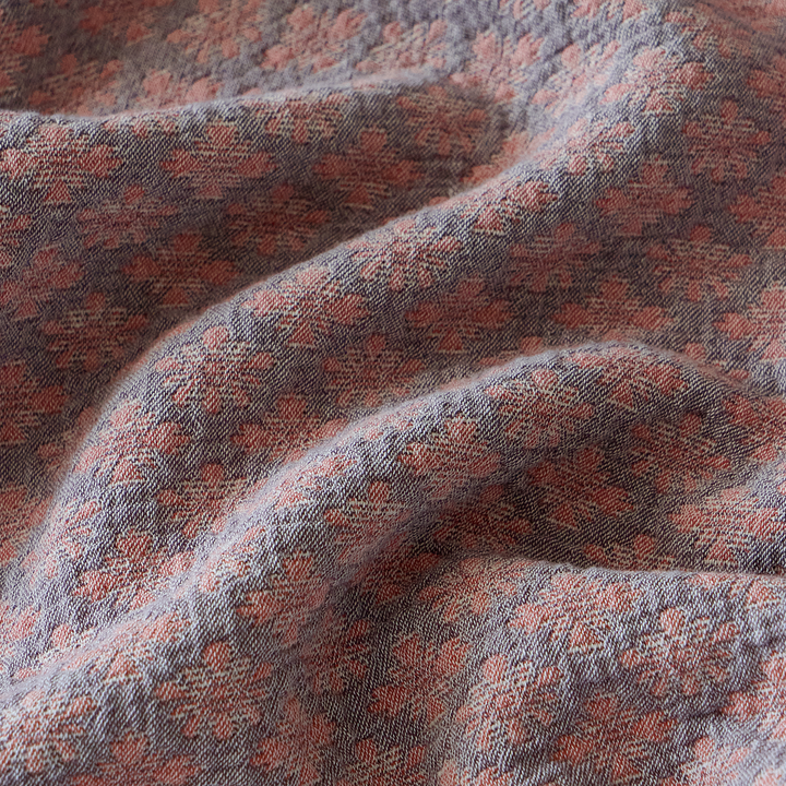 Close-up of the dusty rose 3D yarn-dyed diamond jacquard fabric showing its natural heavy-wash wrinkles.