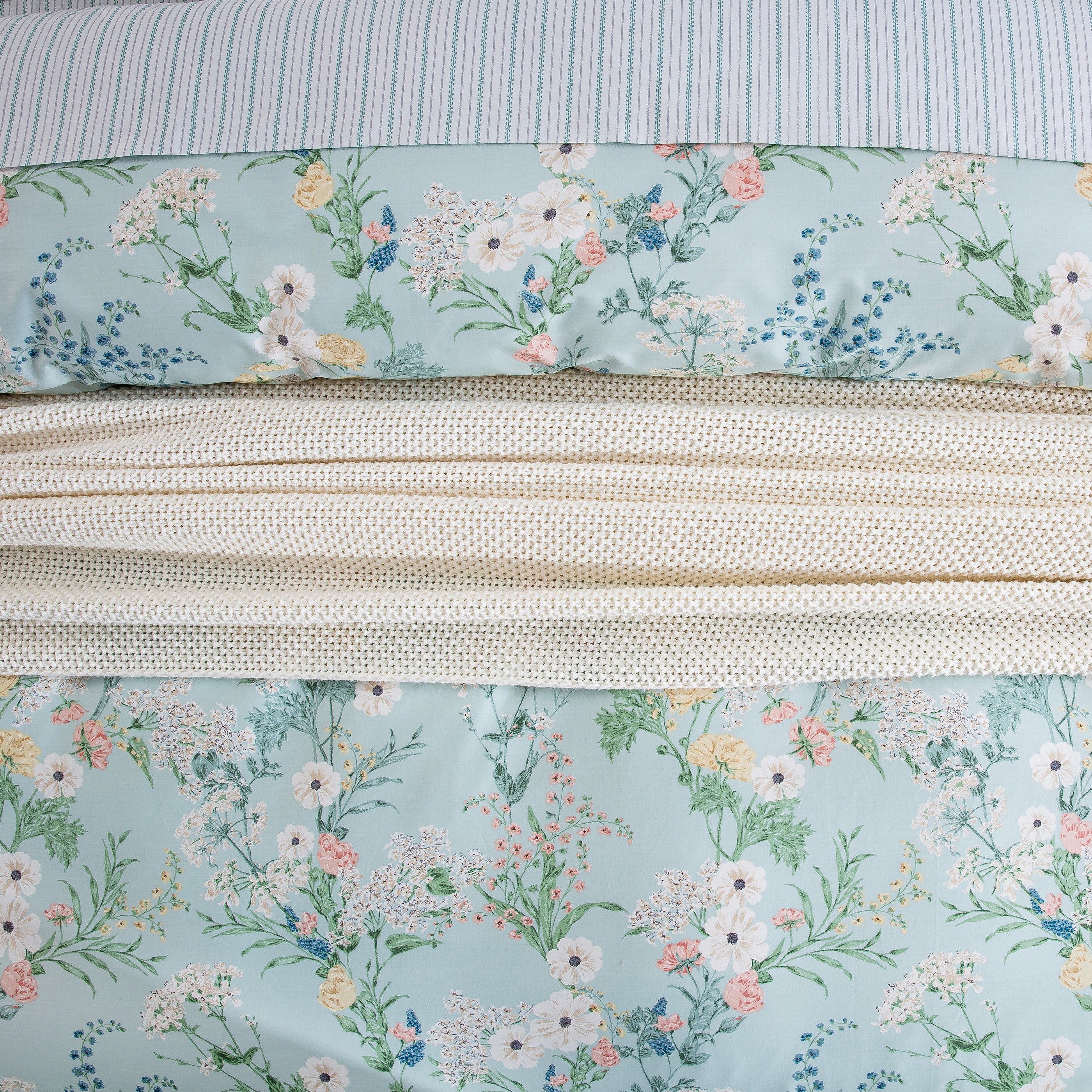 Close-up showing the layered styling of DAUAOTO mint floral duvet cover over light blue striped cotton sheets.