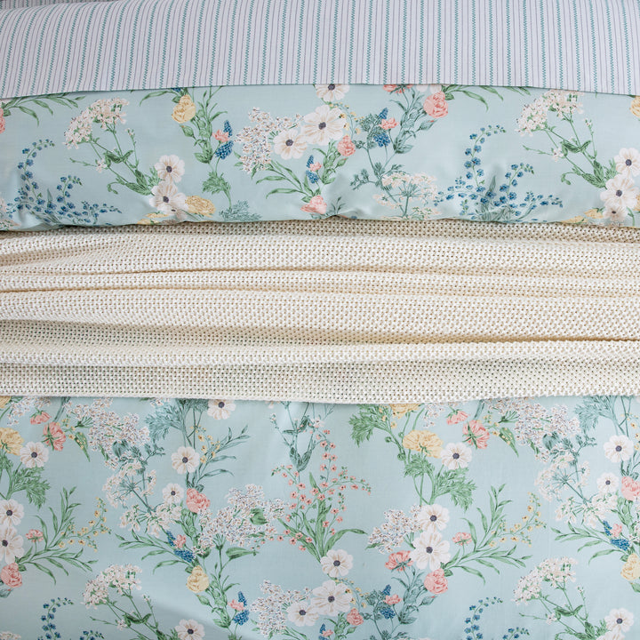 Close-up showing the layered styling of DAUAOTO mint floral duvet cover over light blue striped cotton sheets.