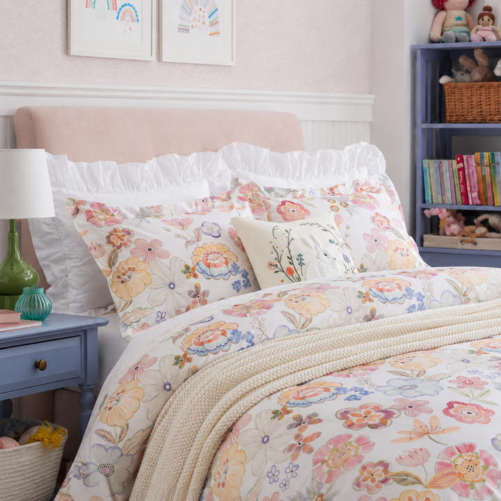 Close-up of the DAUAOTO pastel blossom floral pillowcases neatly arranged on a bed next to a blue nightstand.