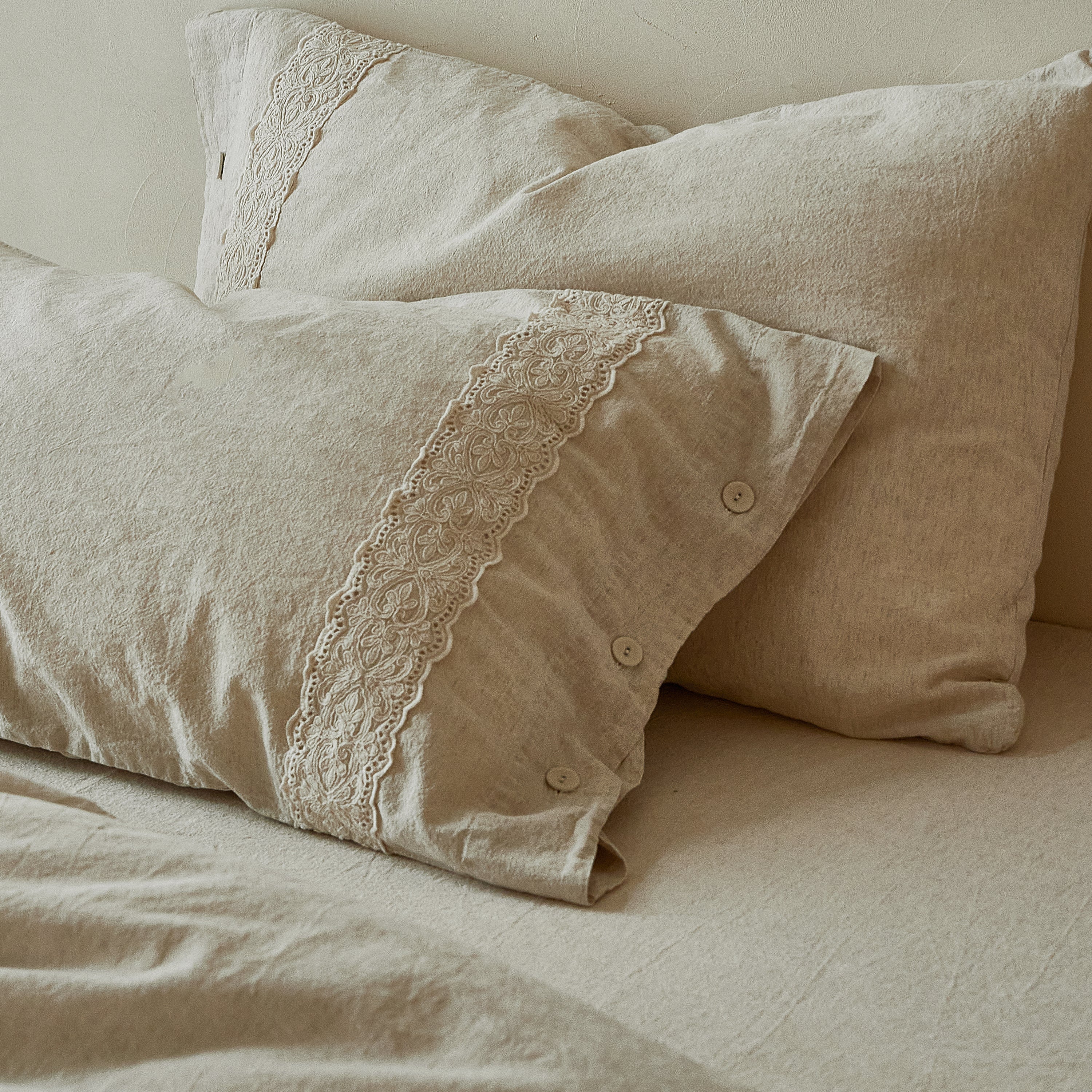 Stacked DAUAOTO Provence linen-cotton pillow shams displaying beautiful embroidered lace details.