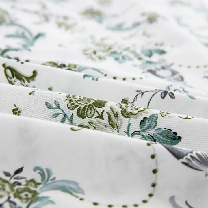 Close-up of ultra-soft pure cotton fabric showing the detailed green floral vine pattern on a warm ivory ground - DAUAOTO