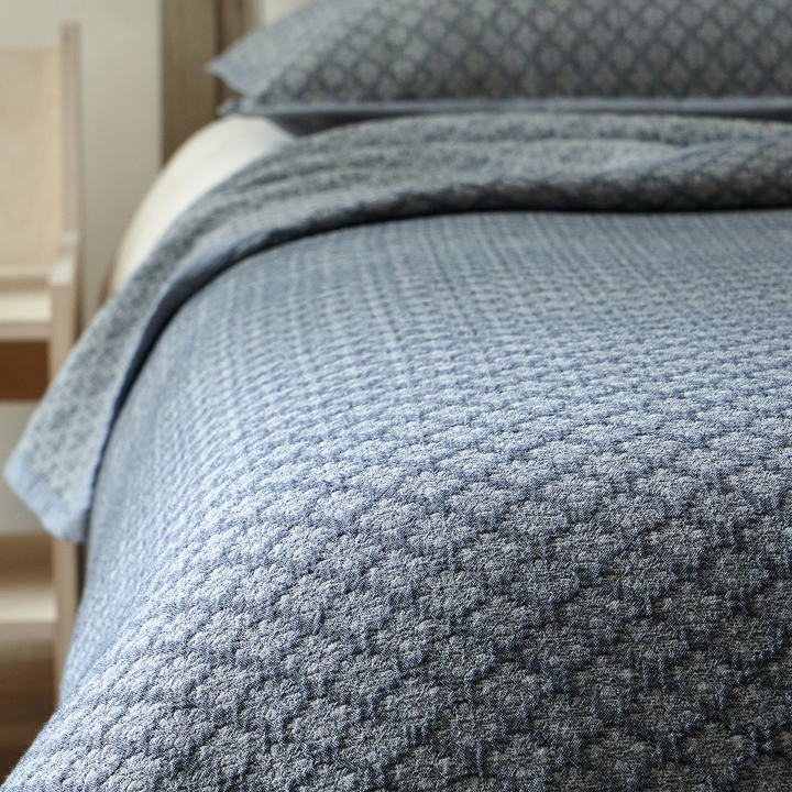 Beautiful heavyweight drape of the slate blue jacquard coverlet cascading over the bed edge.