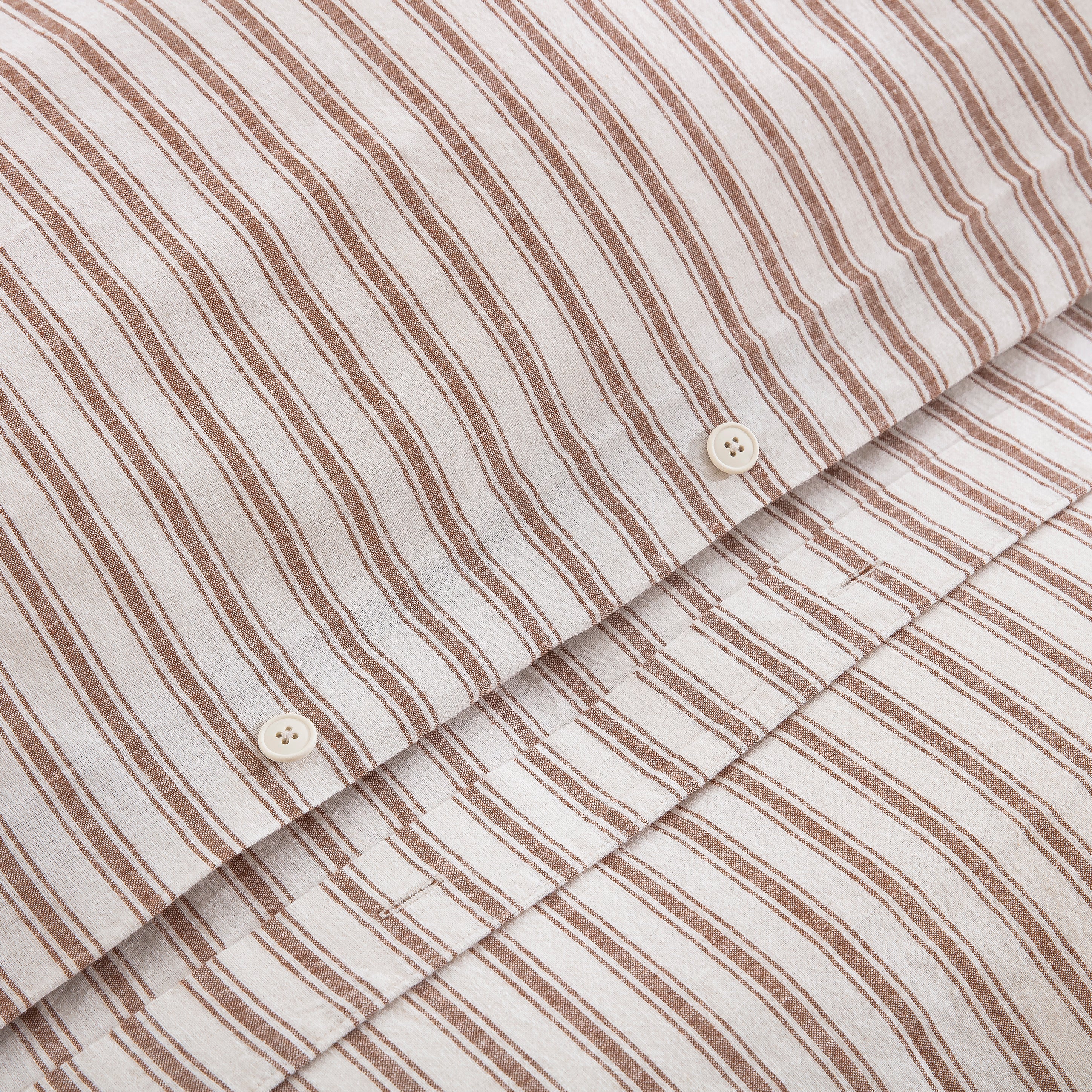 Premium craftsmanship showing a discreet hidden button closure on the caramel yarn-dyed stripe duvet - DAUAOTO