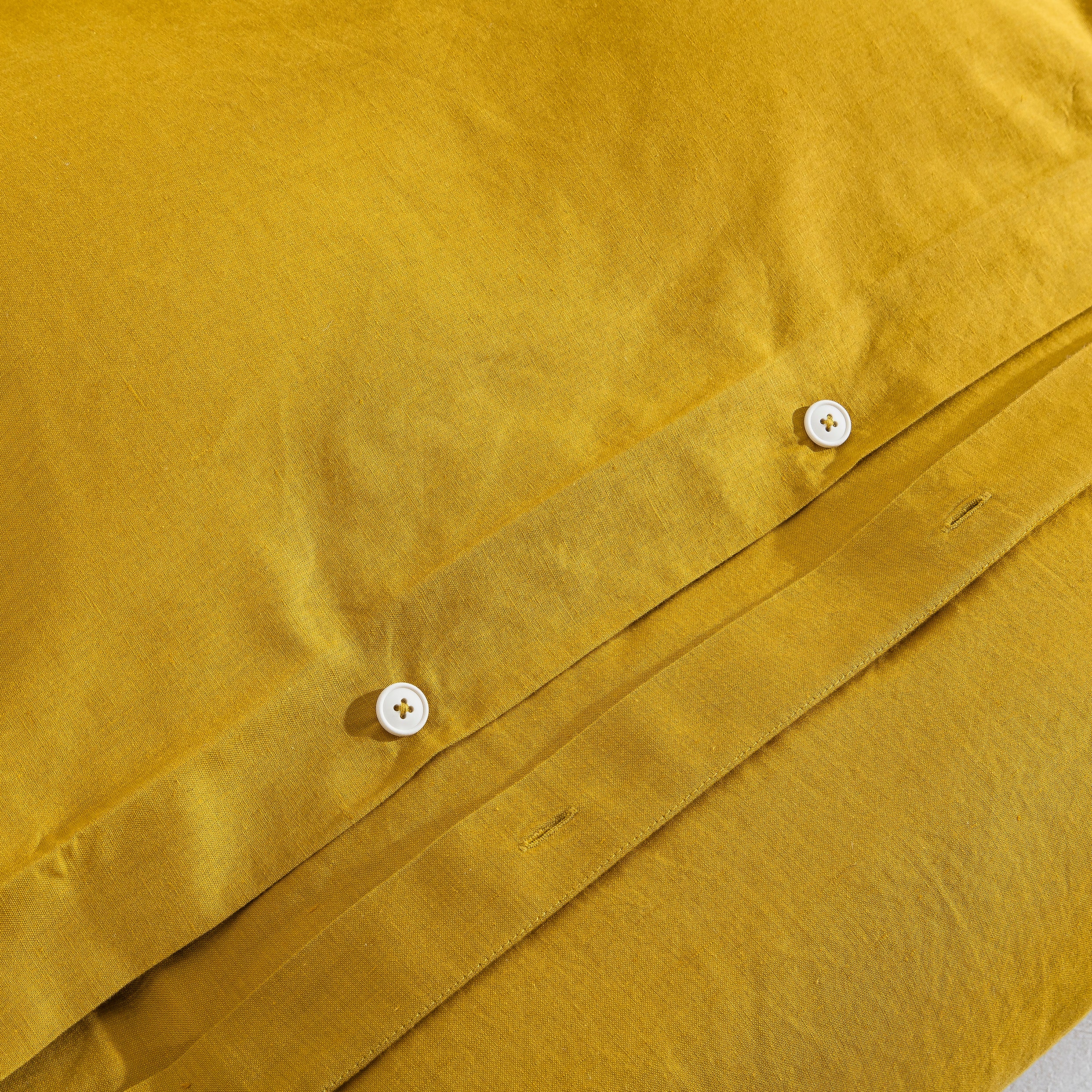 Discreet hidden button closure on the mustard yellow duvet representing traditional premium craftsmanship - DAUAOTO