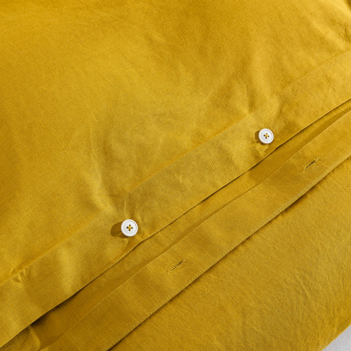 Discreet hidden button closure on the mustard yellow duvet representing traditional premium craftsmanship - DAUAOTO