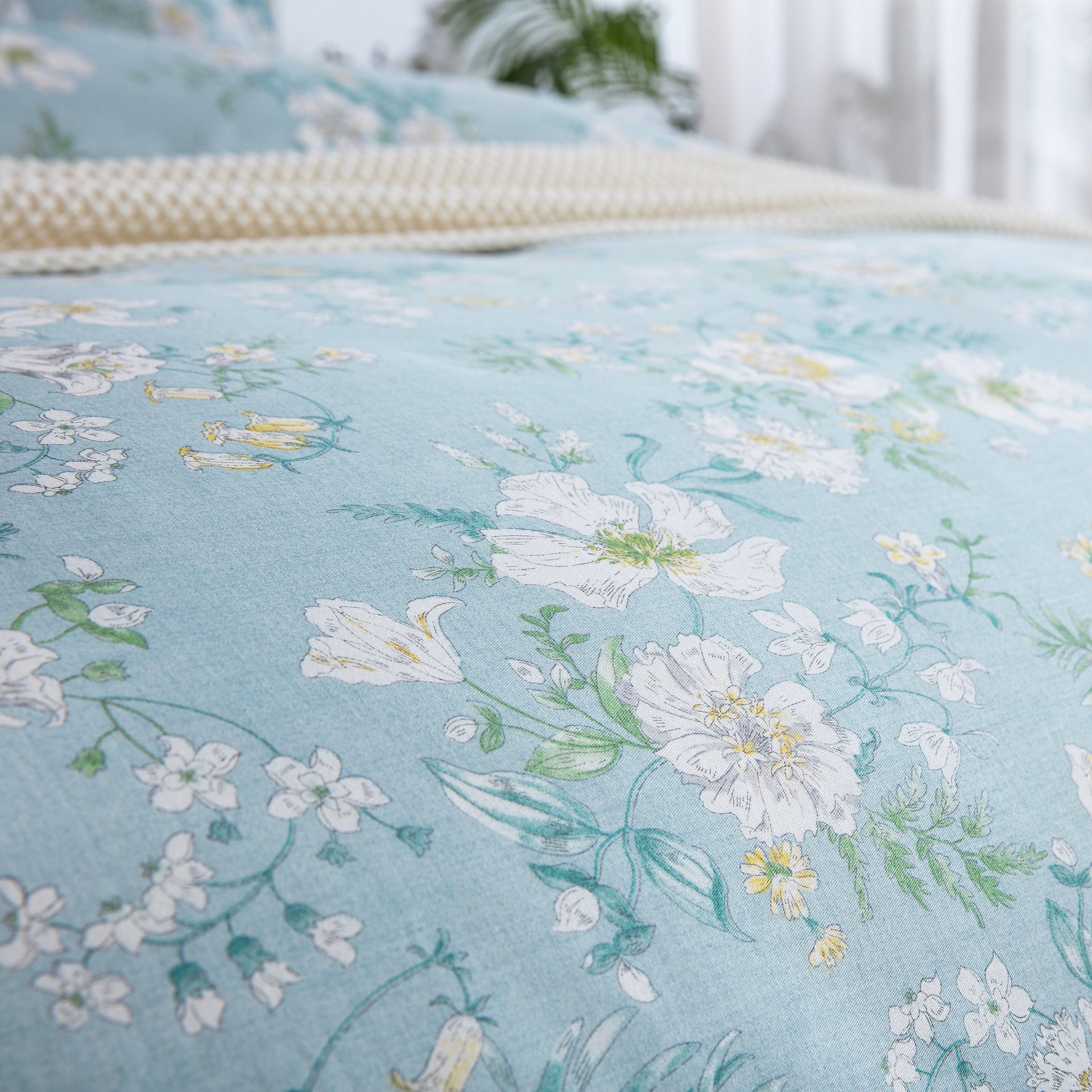 Close-up of DAUAOTO lightweight cotton fabric featuring a light blue base with elegant white and yellow summer blooms.