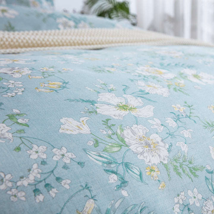 Close-up of DAUAOTO lightweight cotton fabric featuring a light blue base with elegant white and yellow summer blooms.